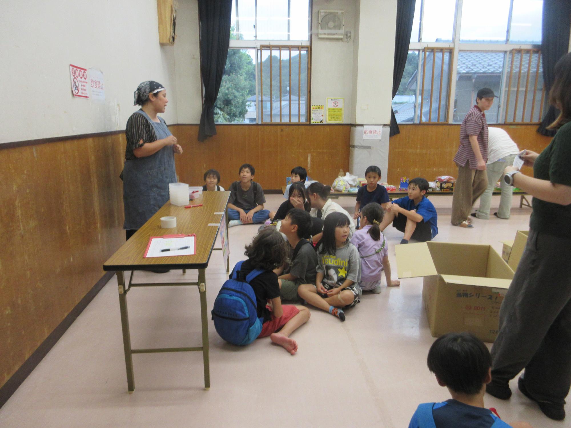 館長が売り子役の児童たちに売り子のやり方と注意事項を説明している様子