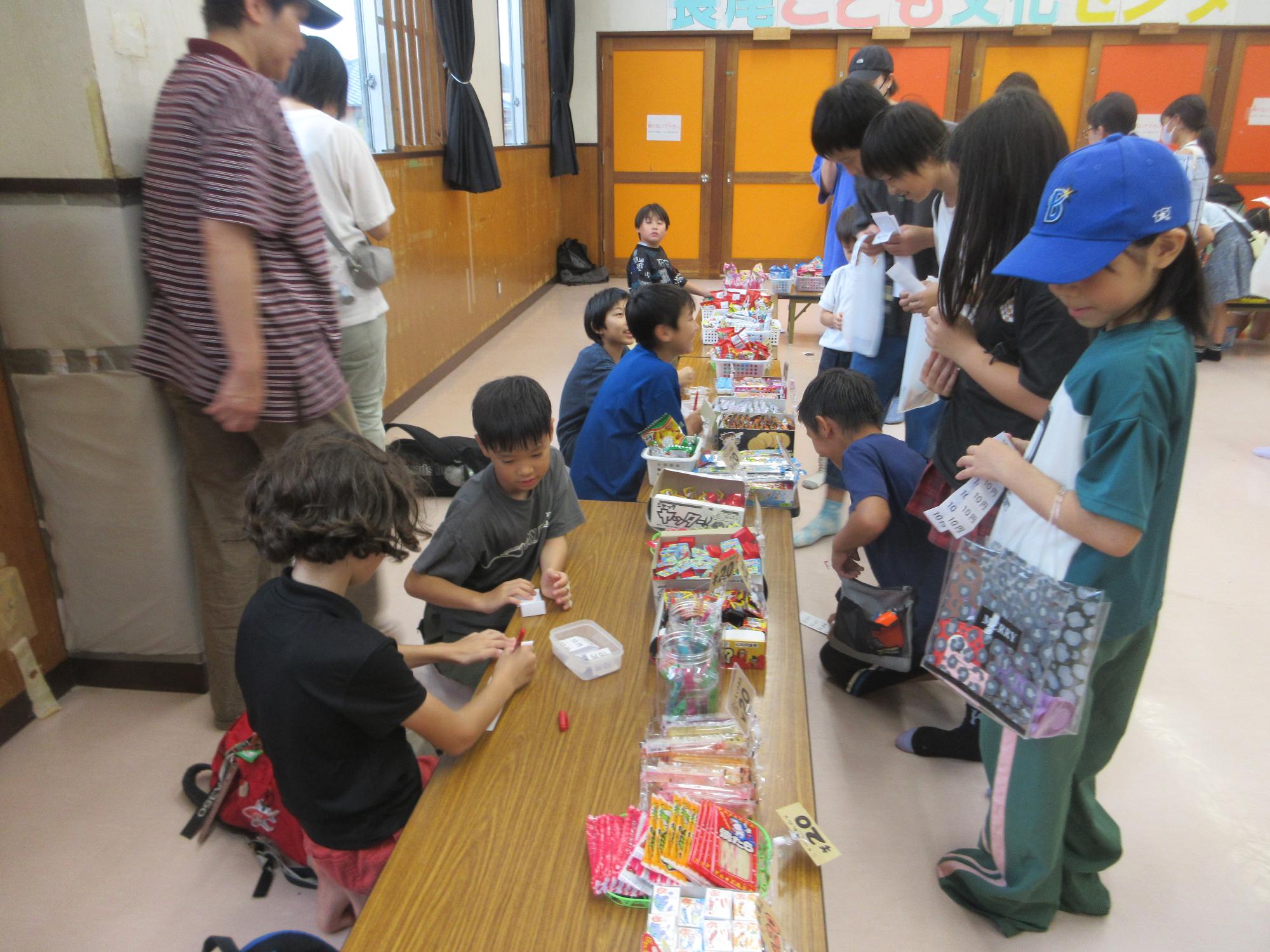 お菓子を選ぶ児童と、金券をチェックする売り子役の児童の様子