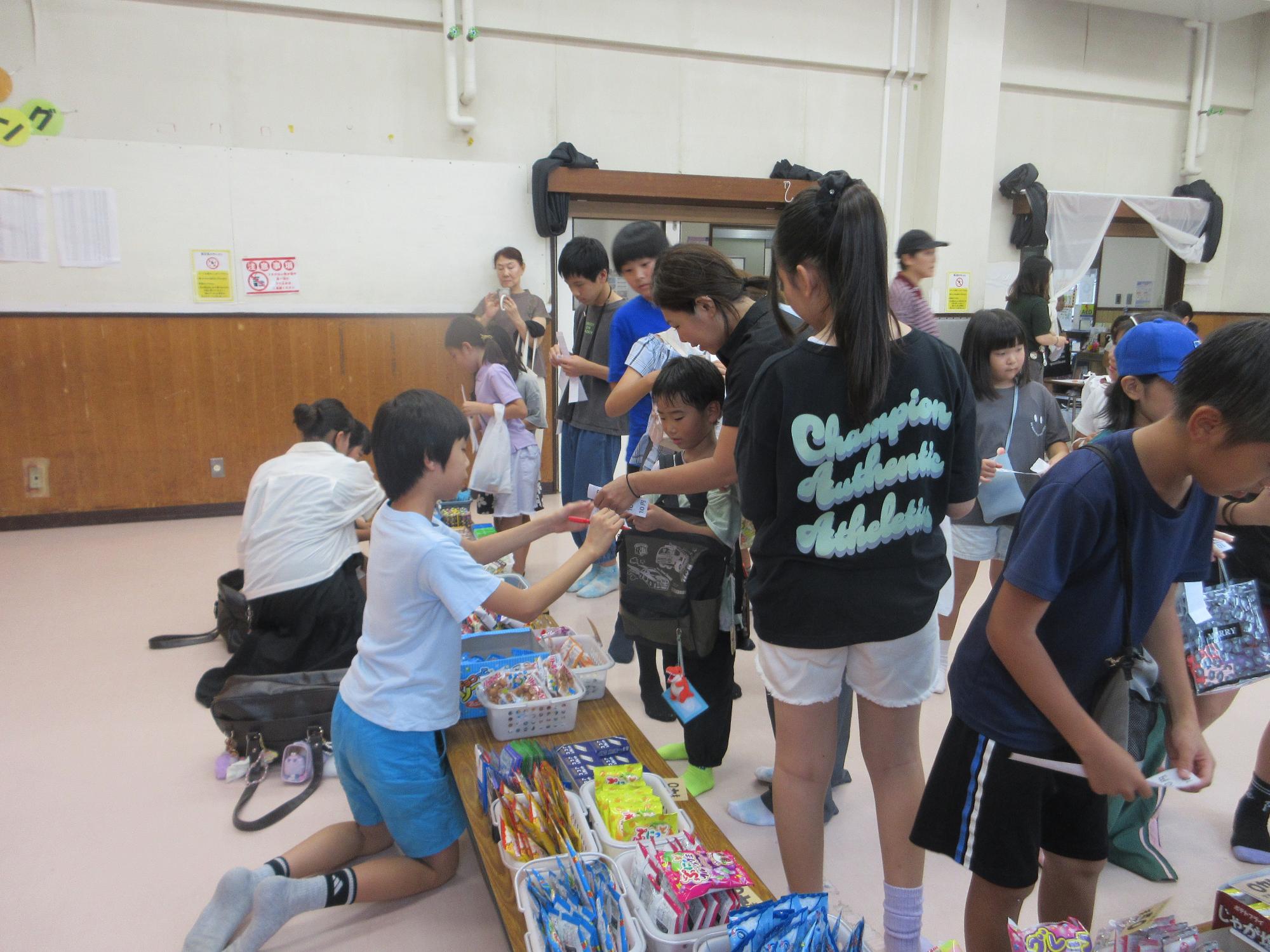 売り子役の児童がお客に商品を渡す様子