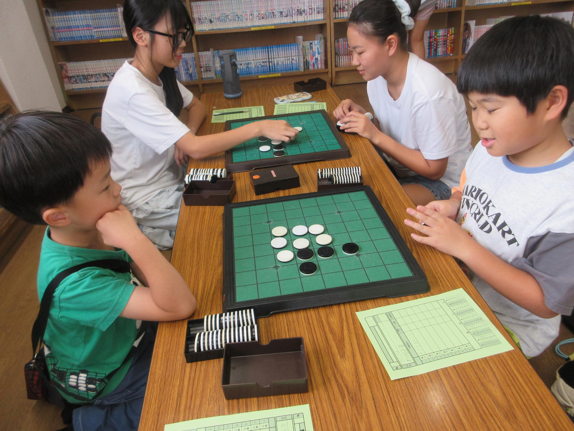オセロ盤をはさんでなごやかに勝負をする子どもたち