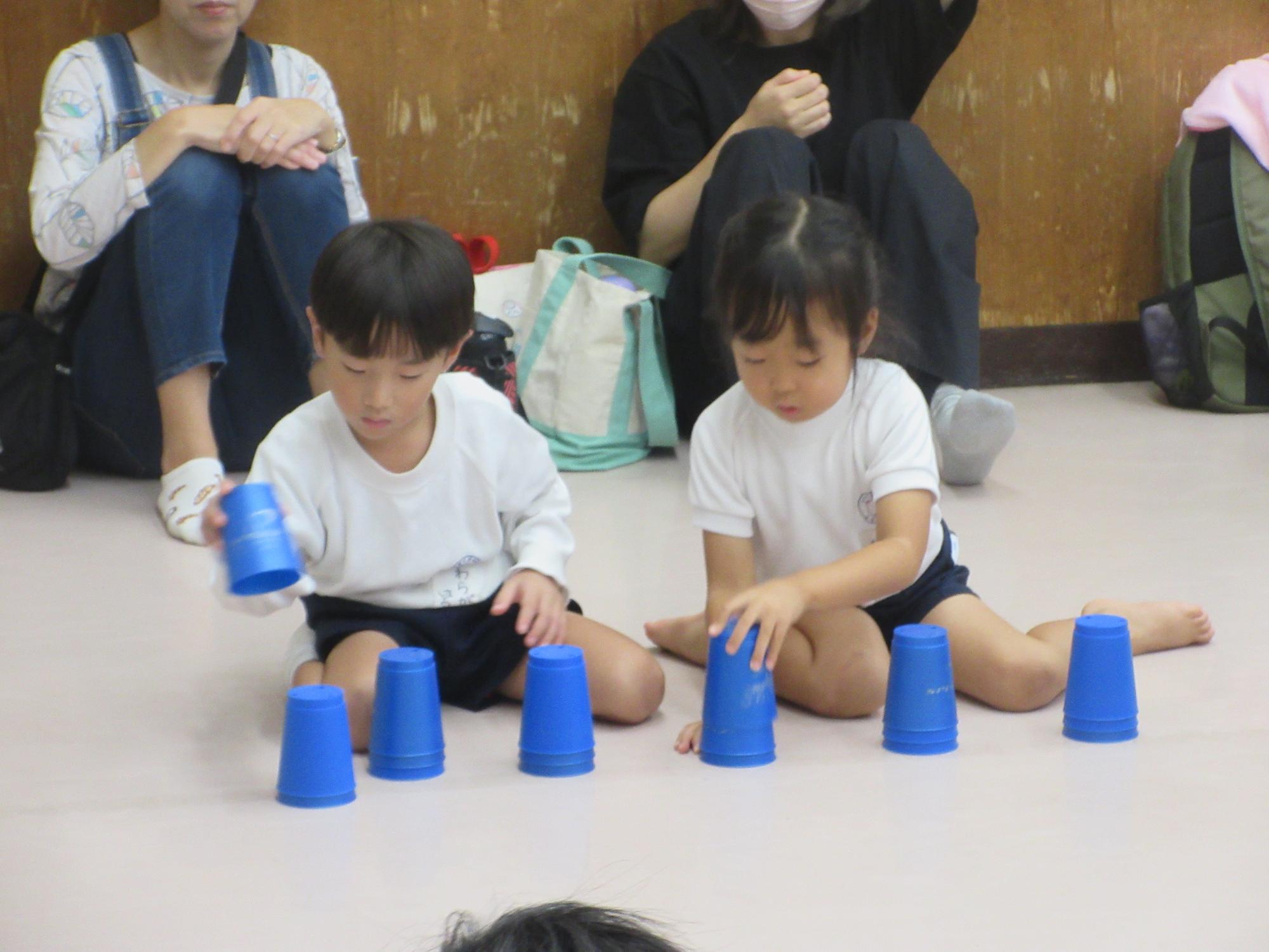 2人の幼児が床で待機しながらスタッキングを練習しているようす