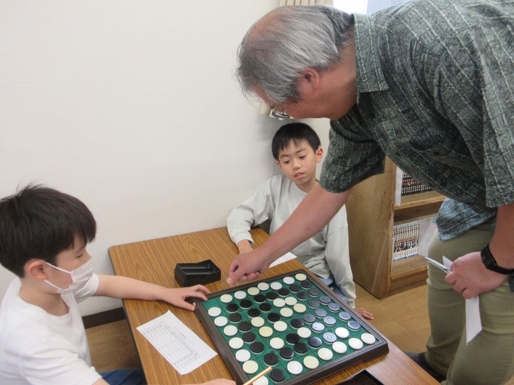 オセロを教わるこどもたちの写真