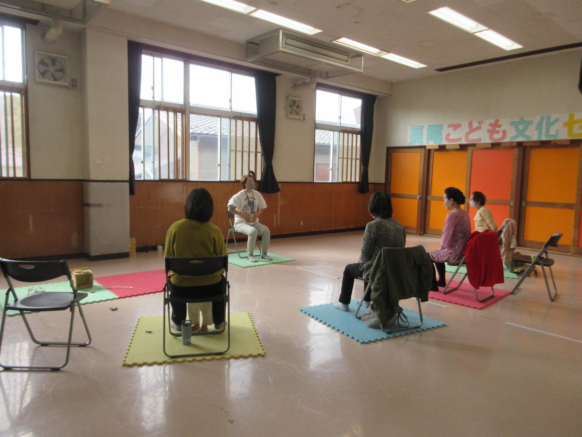 椅子ヨガをする人たちの写真