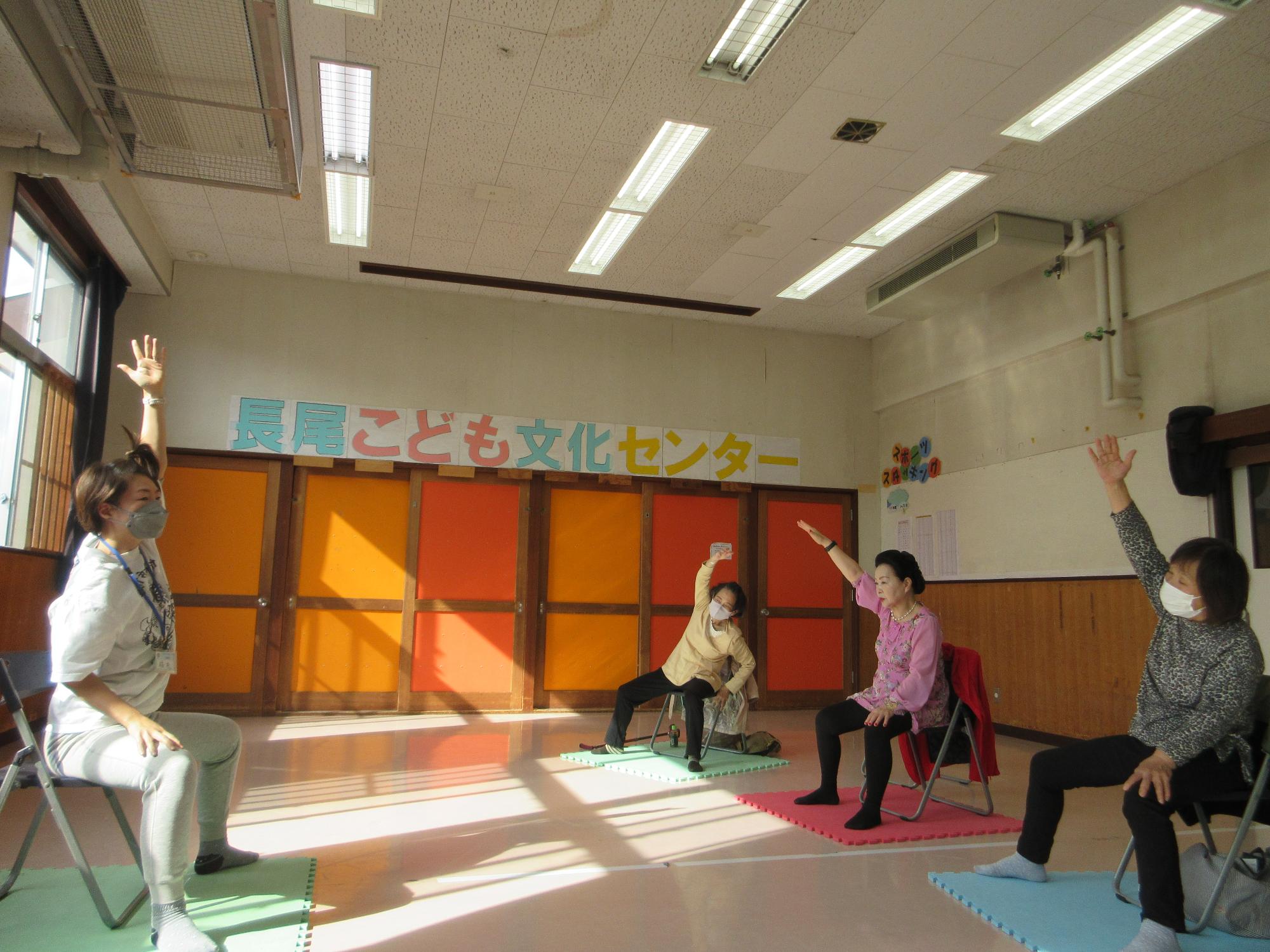 椅子ヨガをする人たちの写真