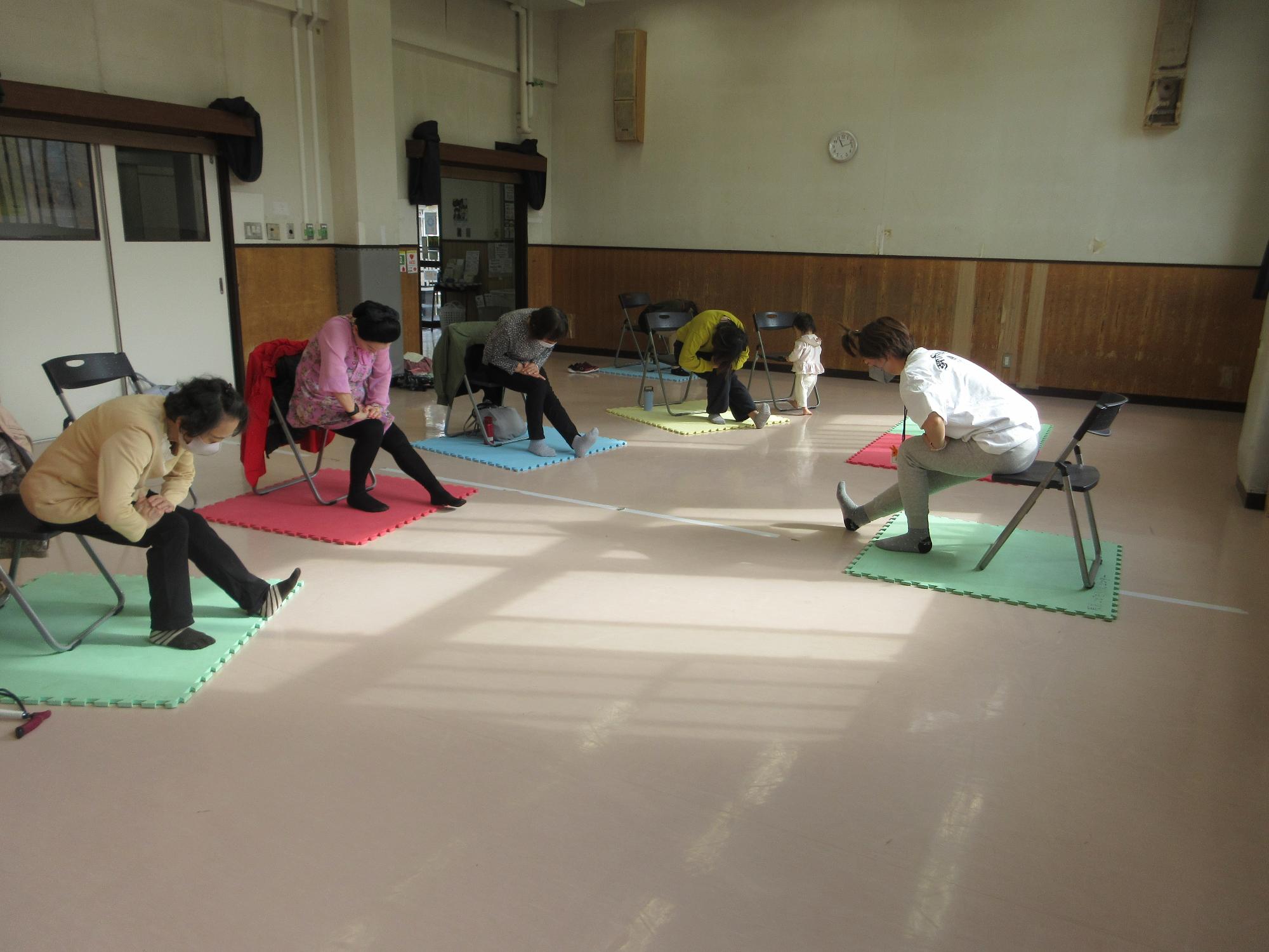 椅子ヨガをする人たちの写真