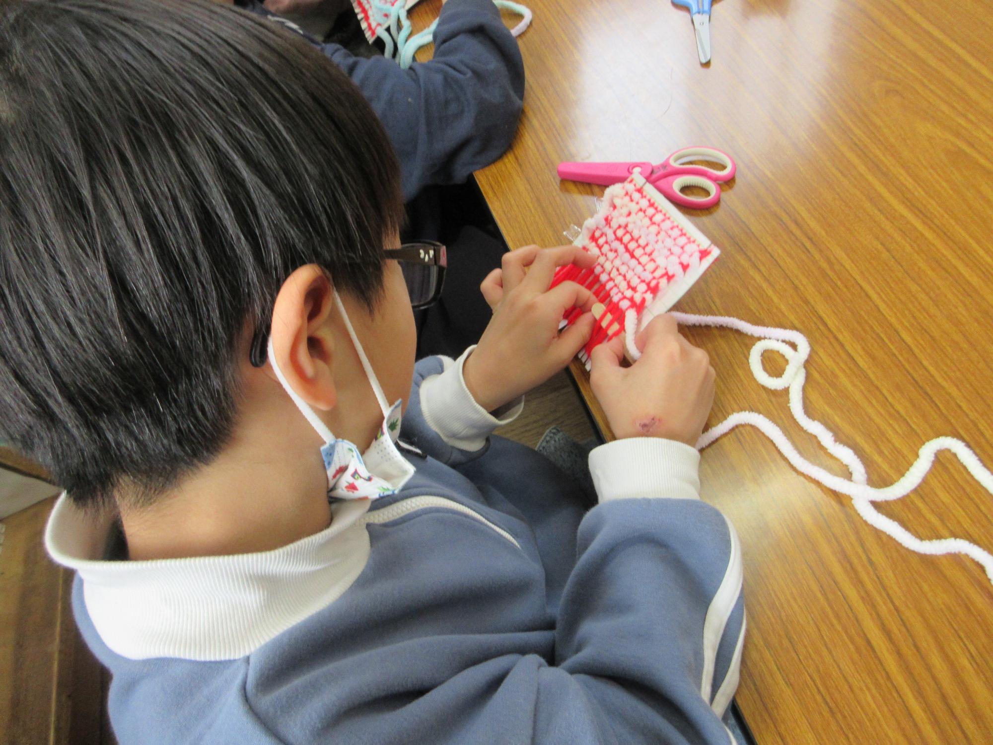 コースターを編んでいるこども