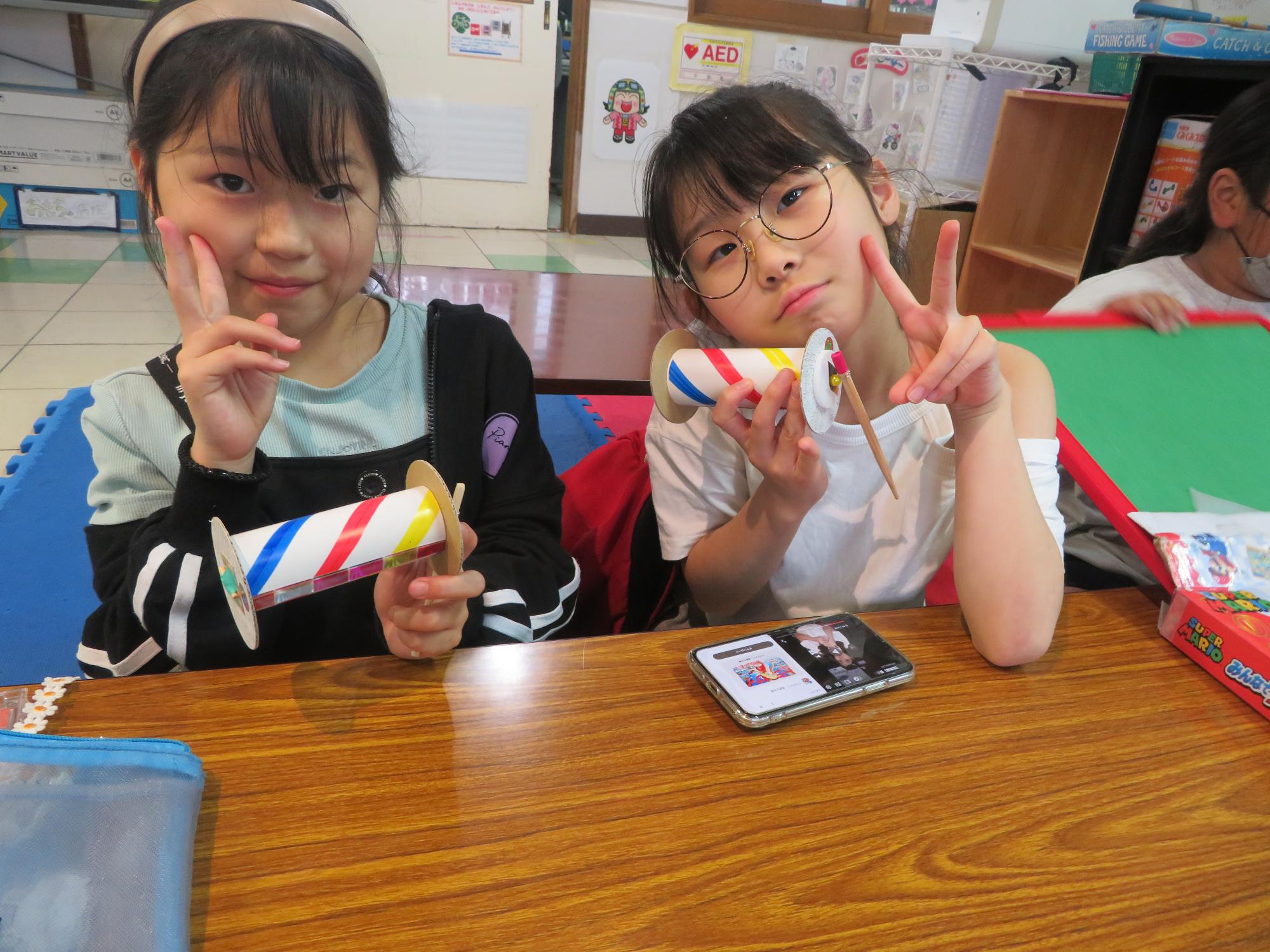 完成品を持ってピースする児童の写真