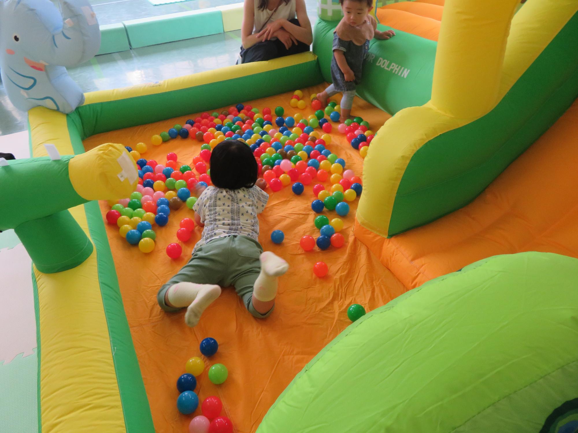ボールプールで寝そべる幼児の写真