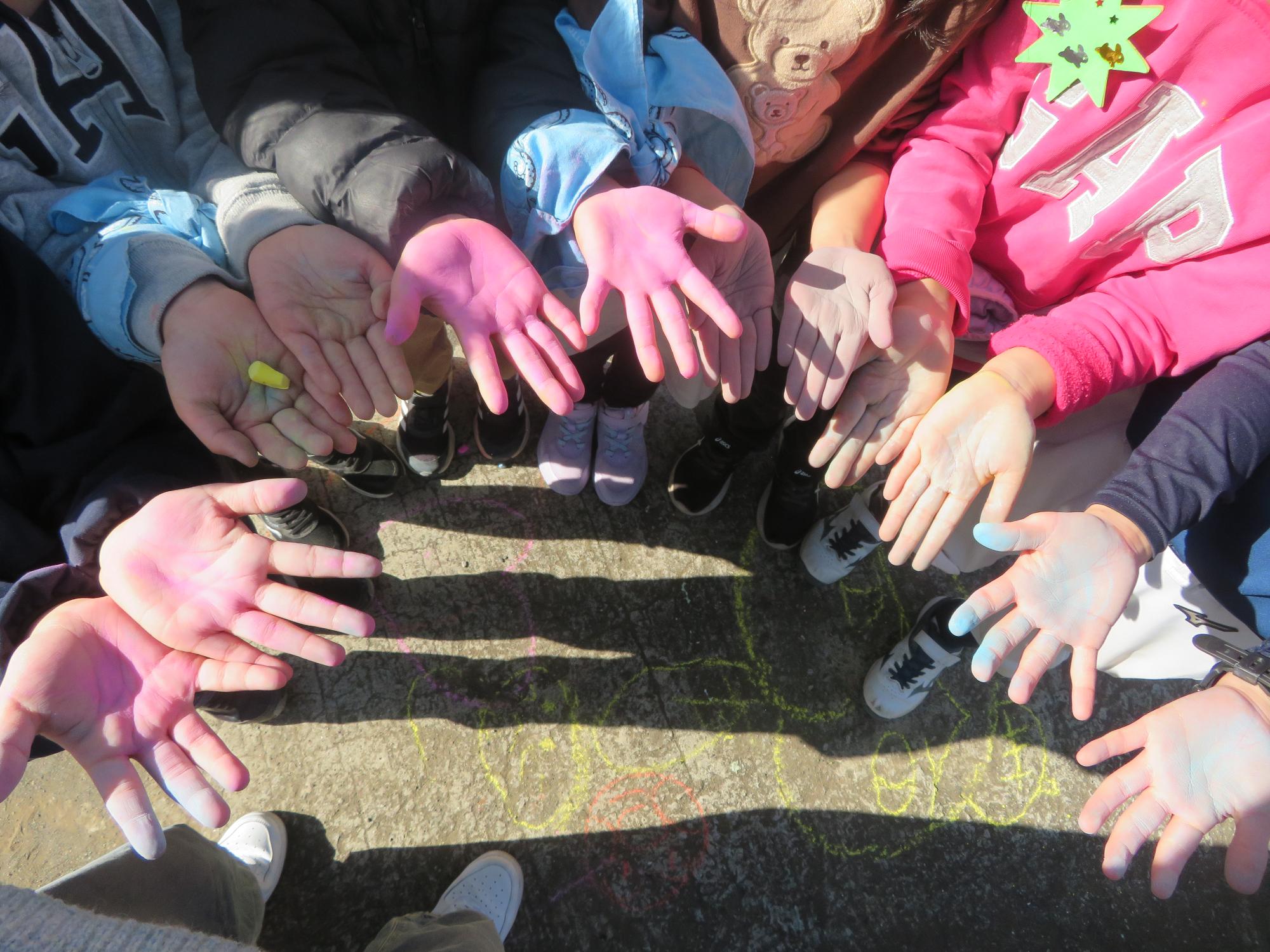 チョークアートをしてカラフルになった子どもたちの手の写真