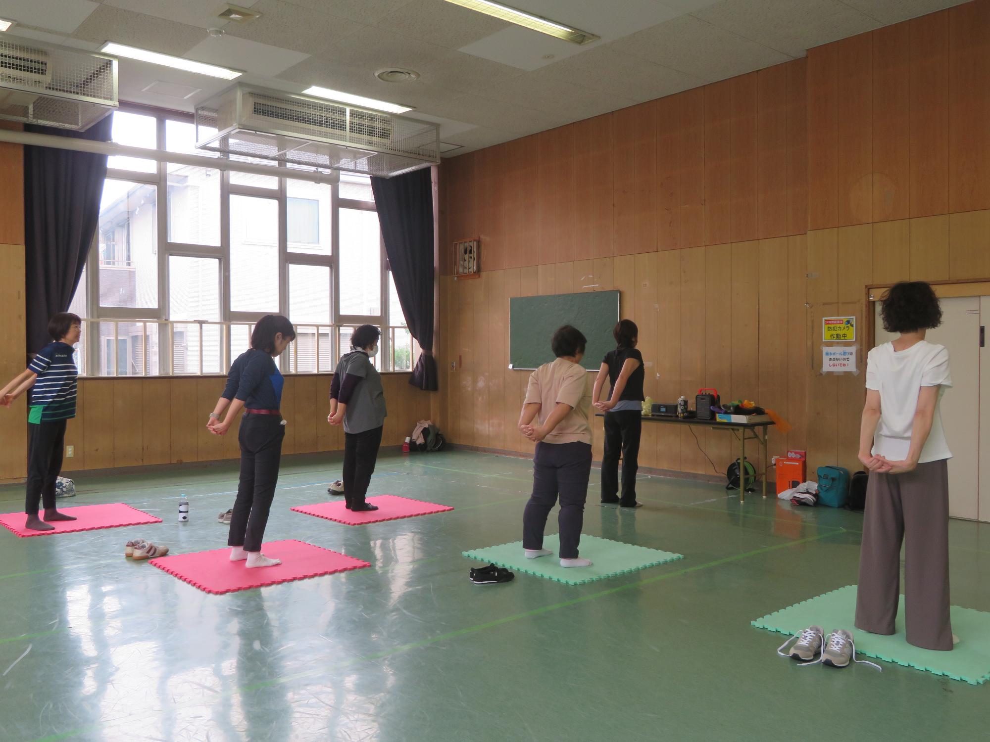 マットの上で体を伸ばす参加者の様子の写真