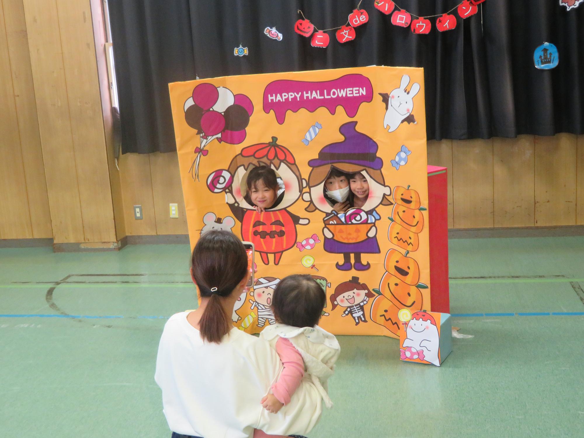 顔はめパネルコーナーで写真を撮る幼児親子の写真