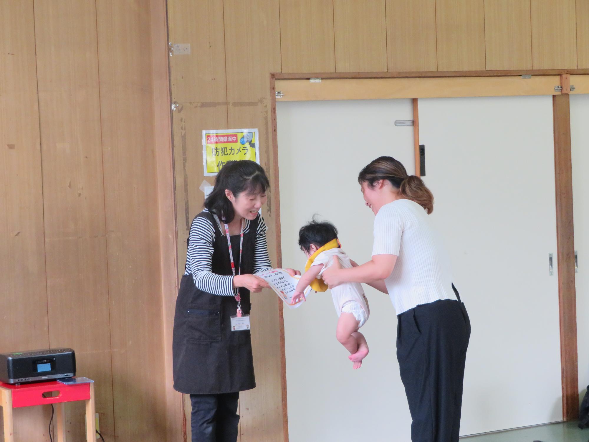 表彰式で賞状を受け取る選手を抱く保護者の写真