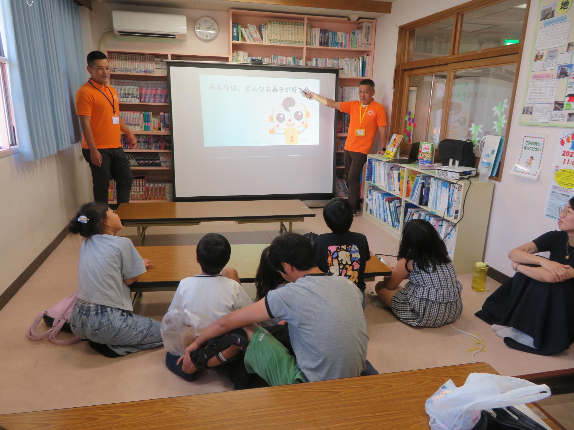図書室で講義を受ける小学生と保護者の写真