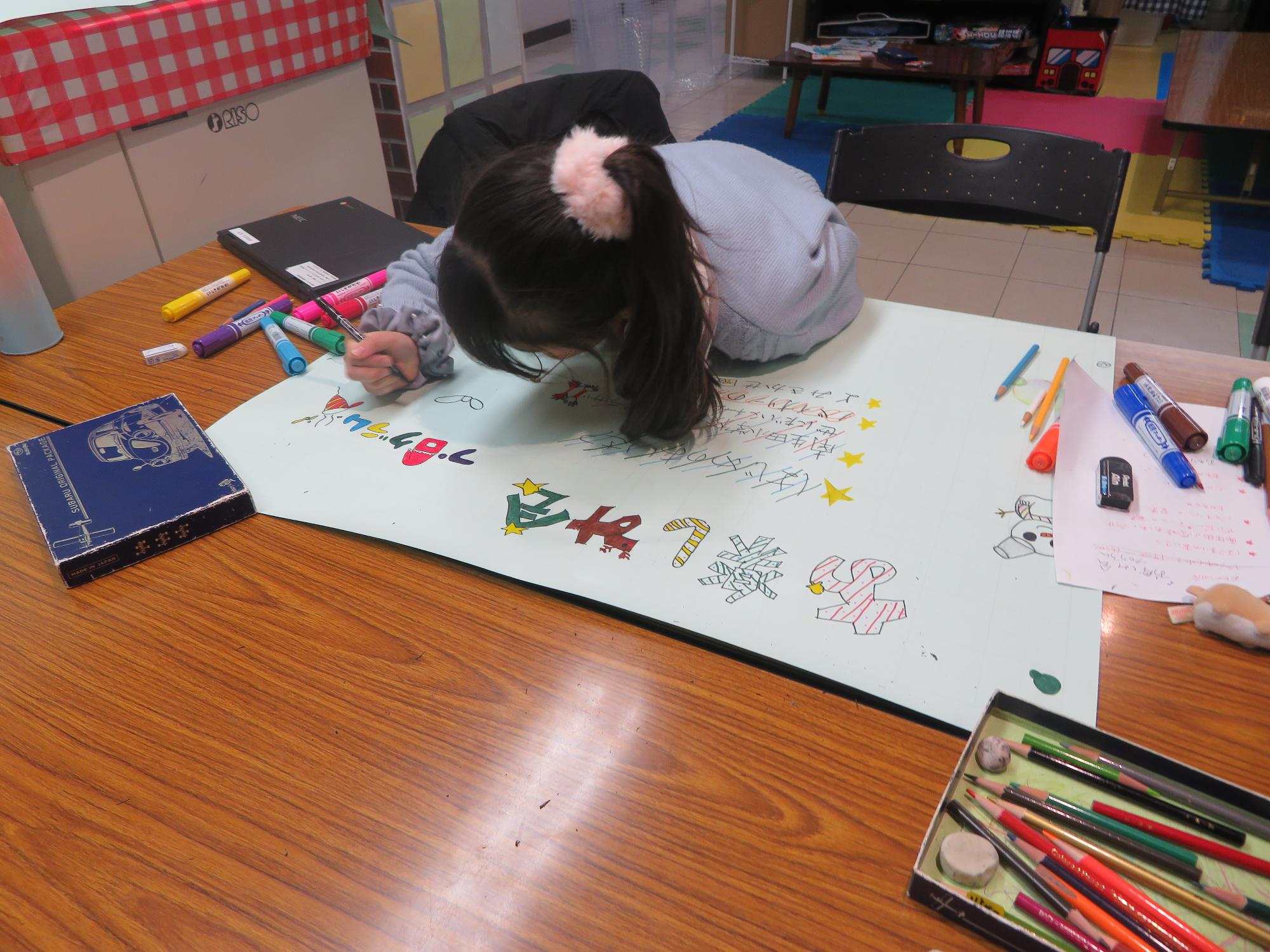 プログラムのポスターを書くこどもの写真