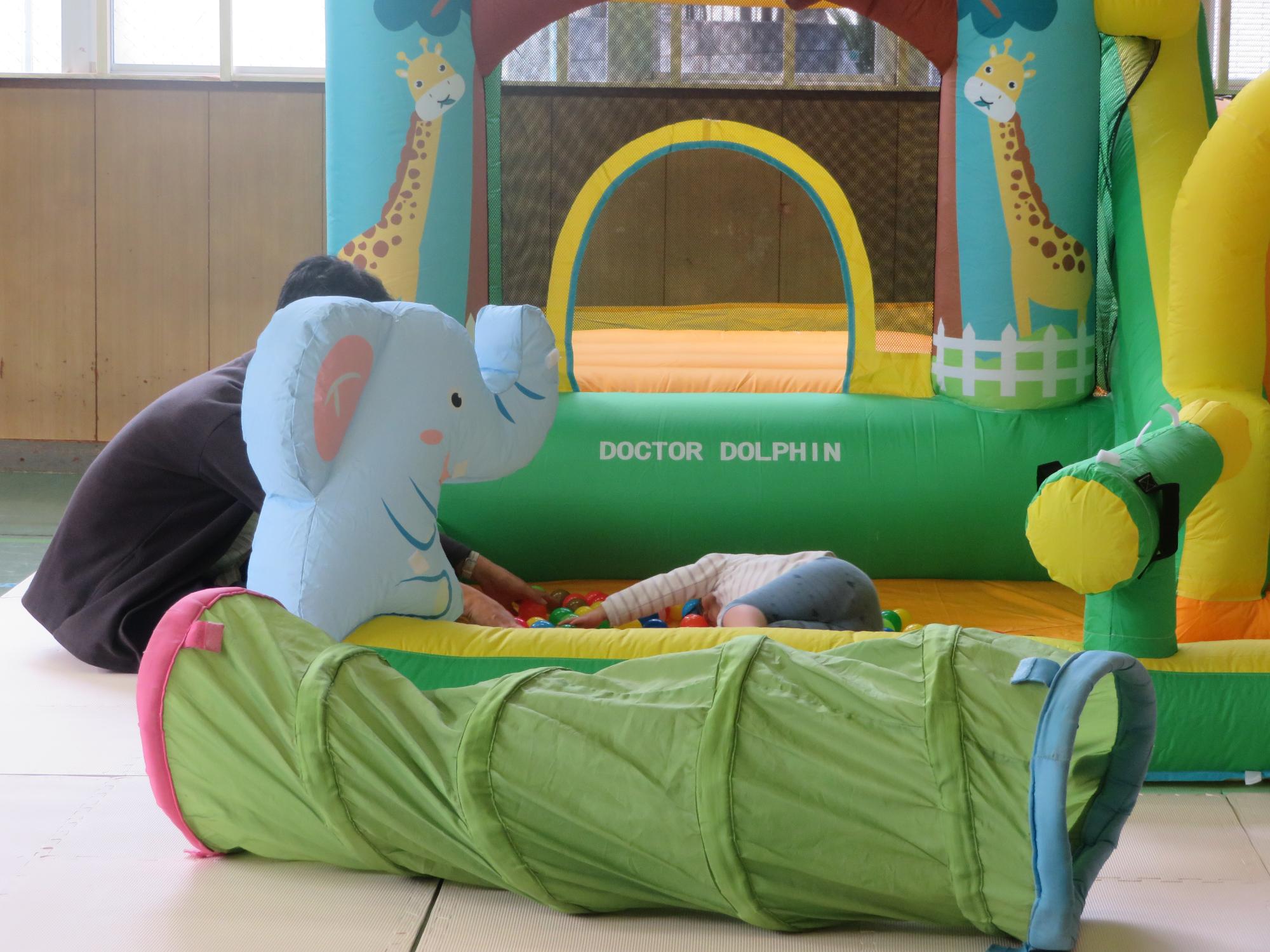 ボールプールで寝転ぶ幼児の写真