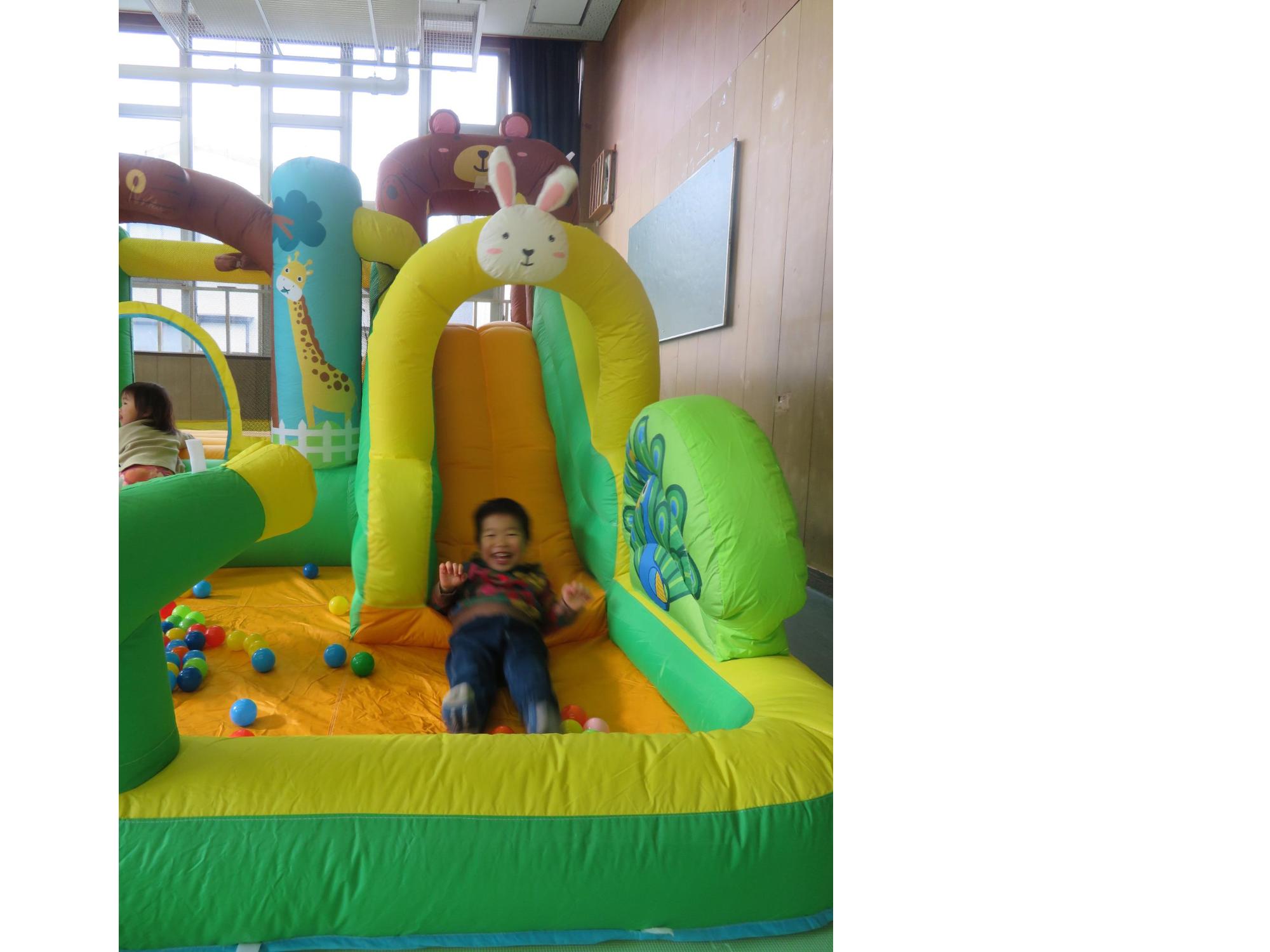 大型エア遊具の滑り台で遊ぶ幼児の写真