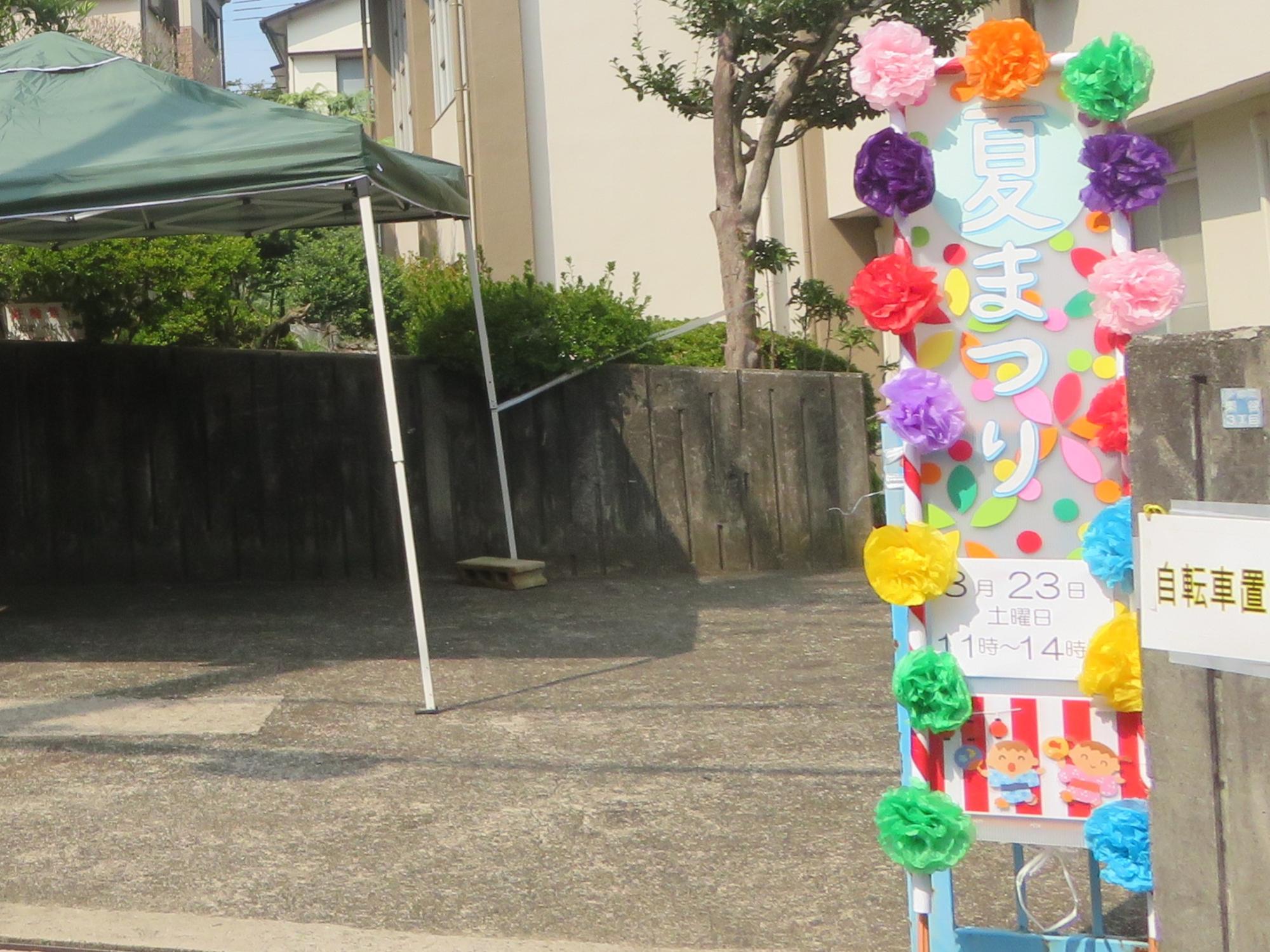 夏祭りの看板、タープを張った駐輪場の写真