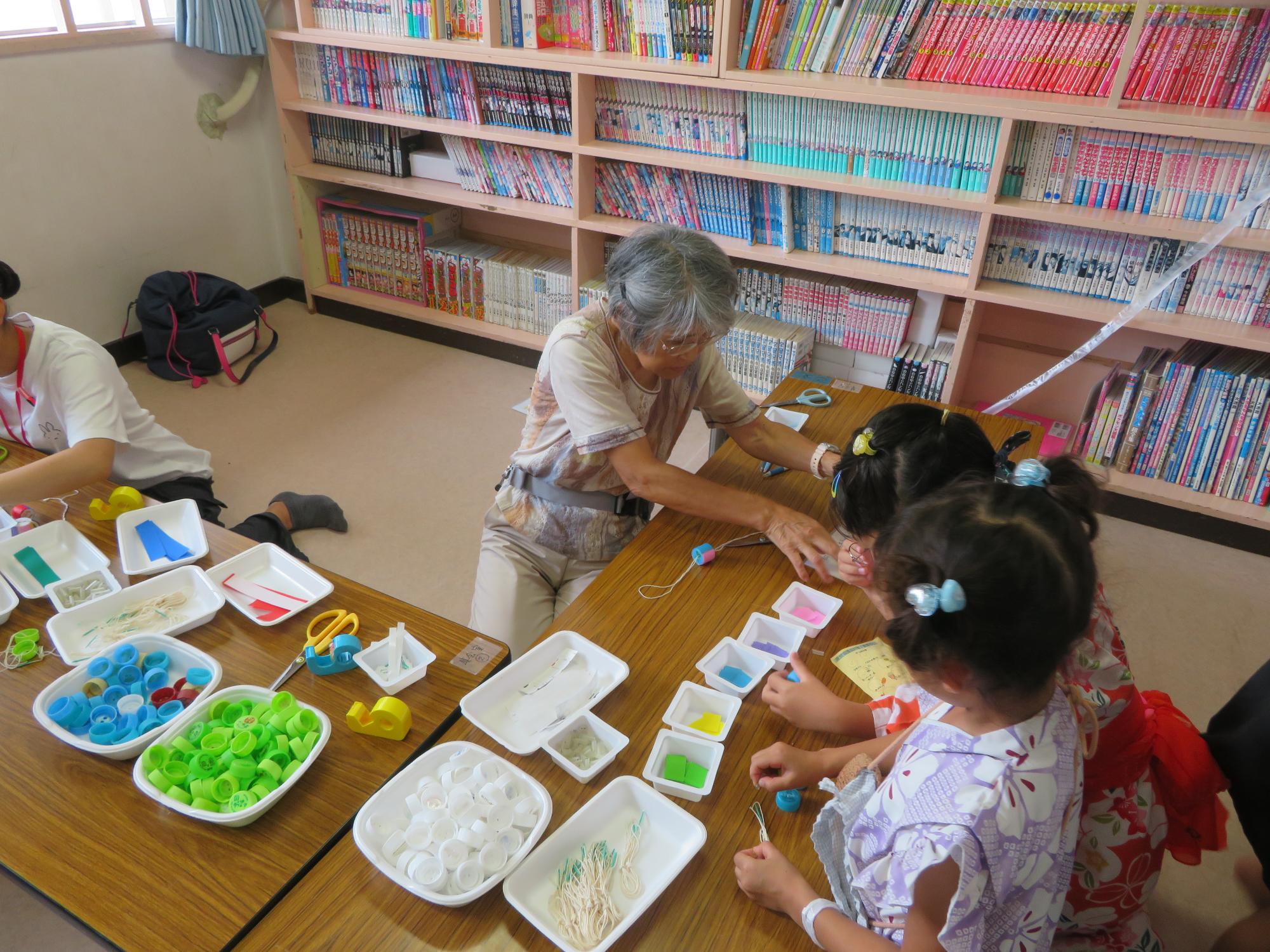 工作ブースで作り方を教える運営協議会委員と作業中の子どもの写真