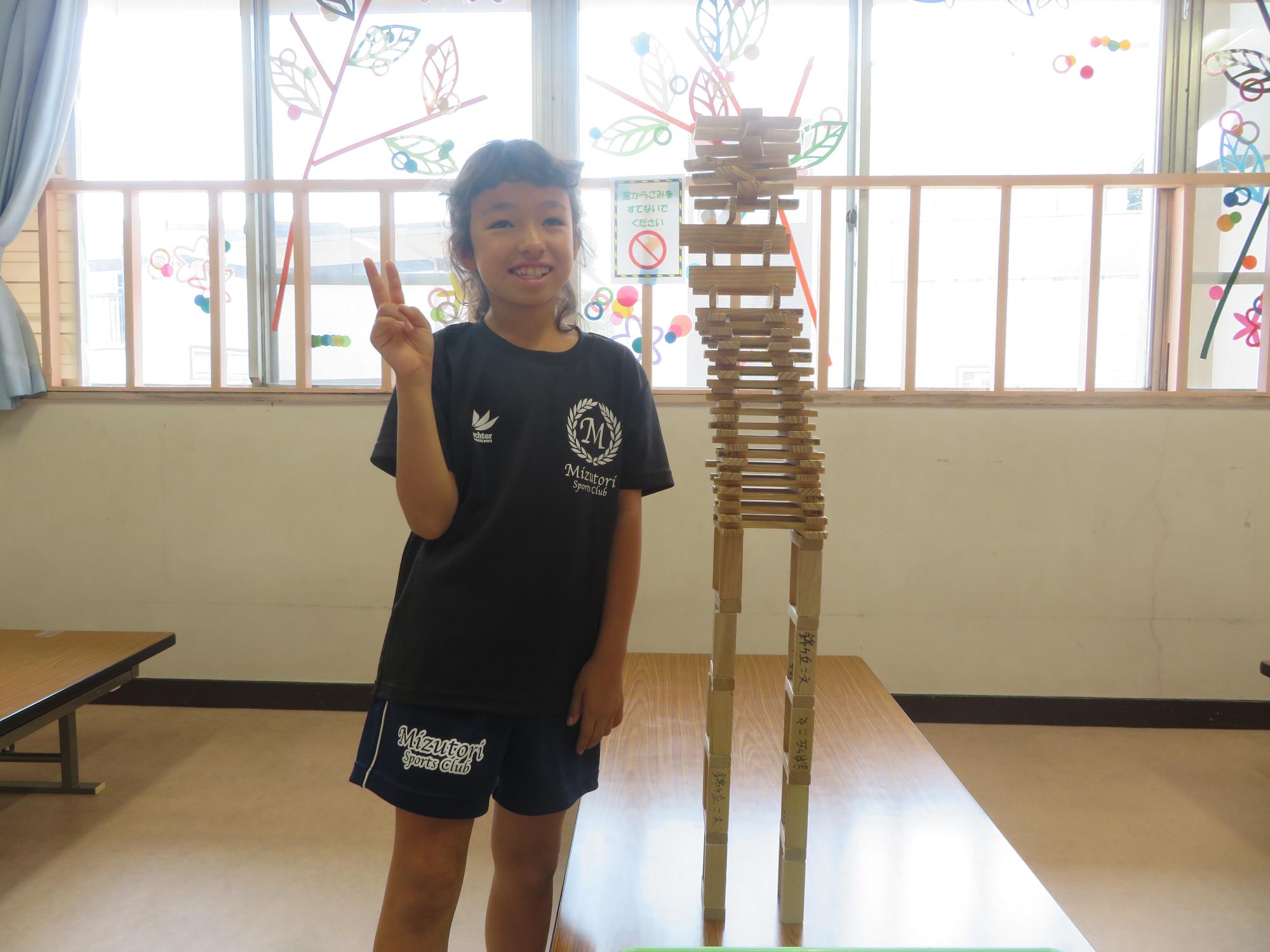 大作の横でピースする小学生の写真