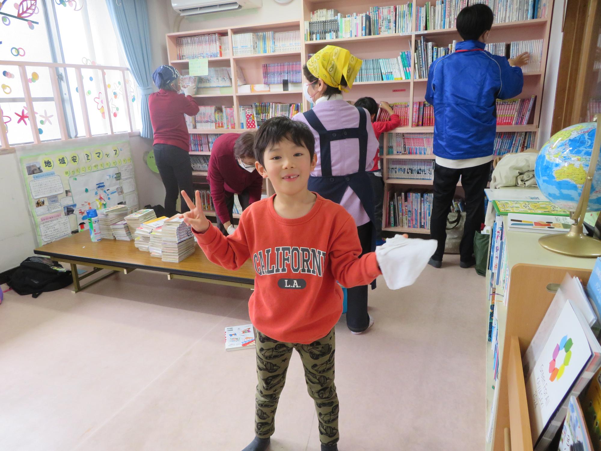 棚を拭いた後カメラに気付いてピースサインをする児童の写真