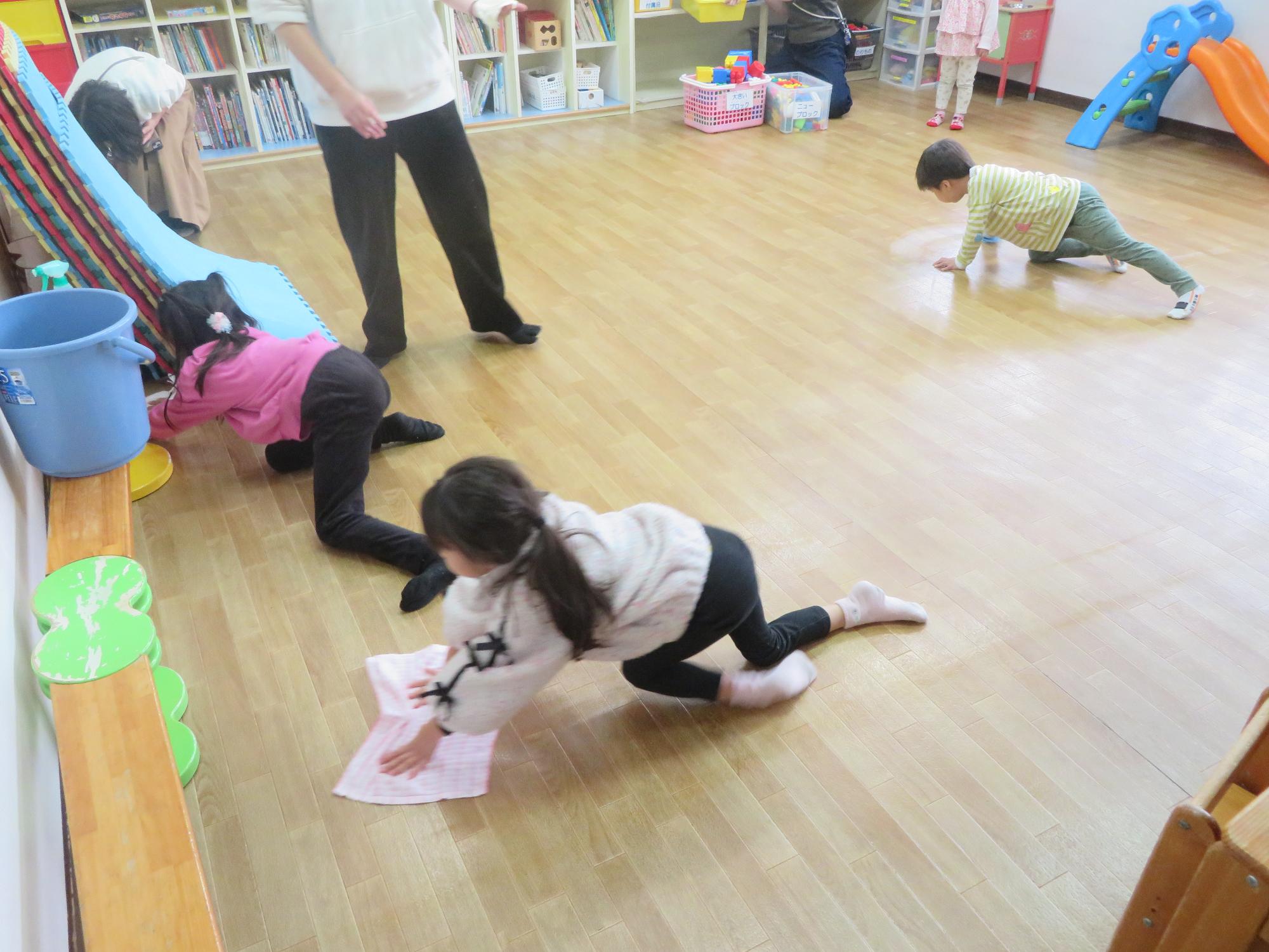 乳幼児室の雑巾がけをする児童たちの写真