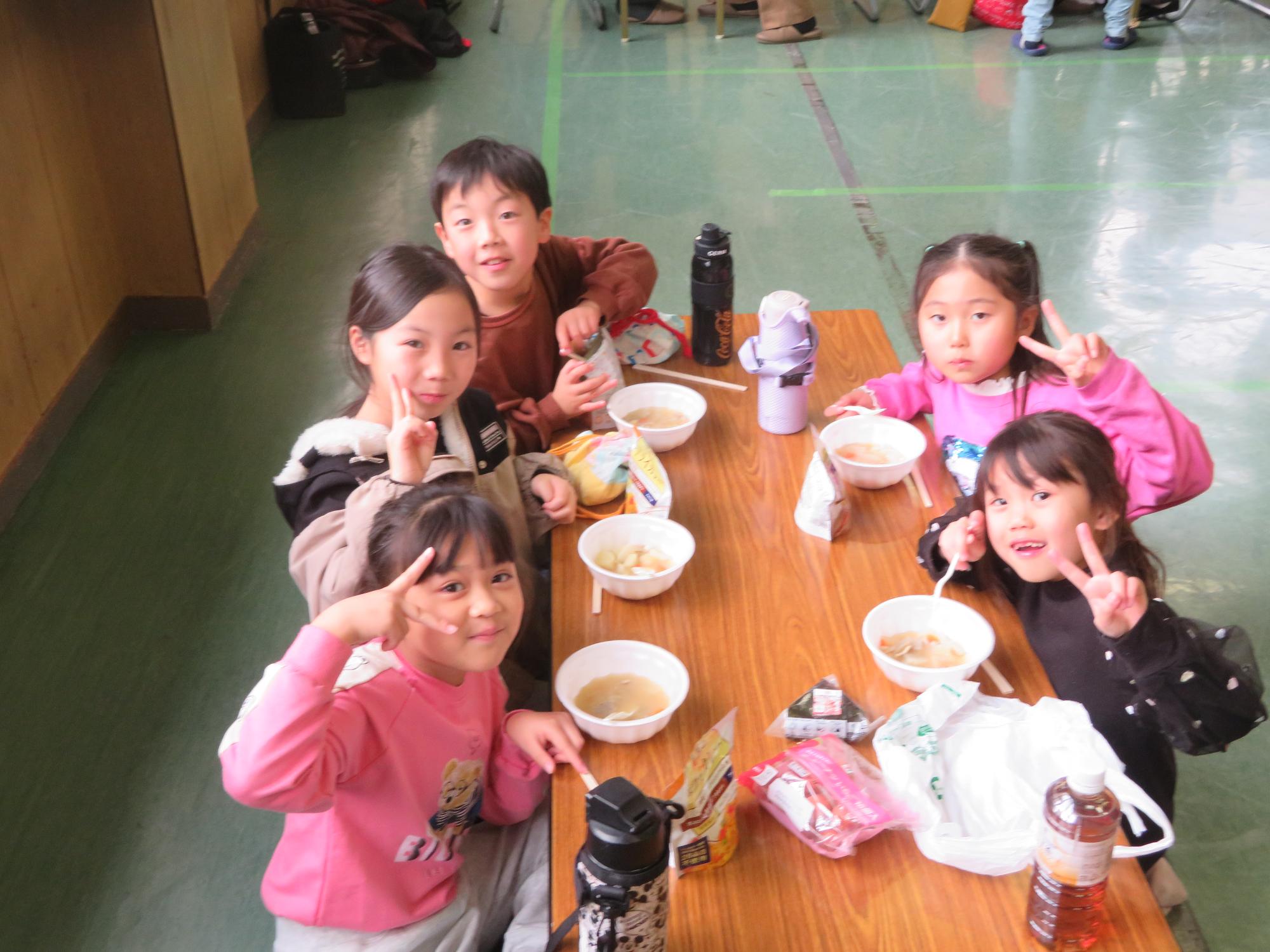 豚汁とアルファ米を食べる児童の写真