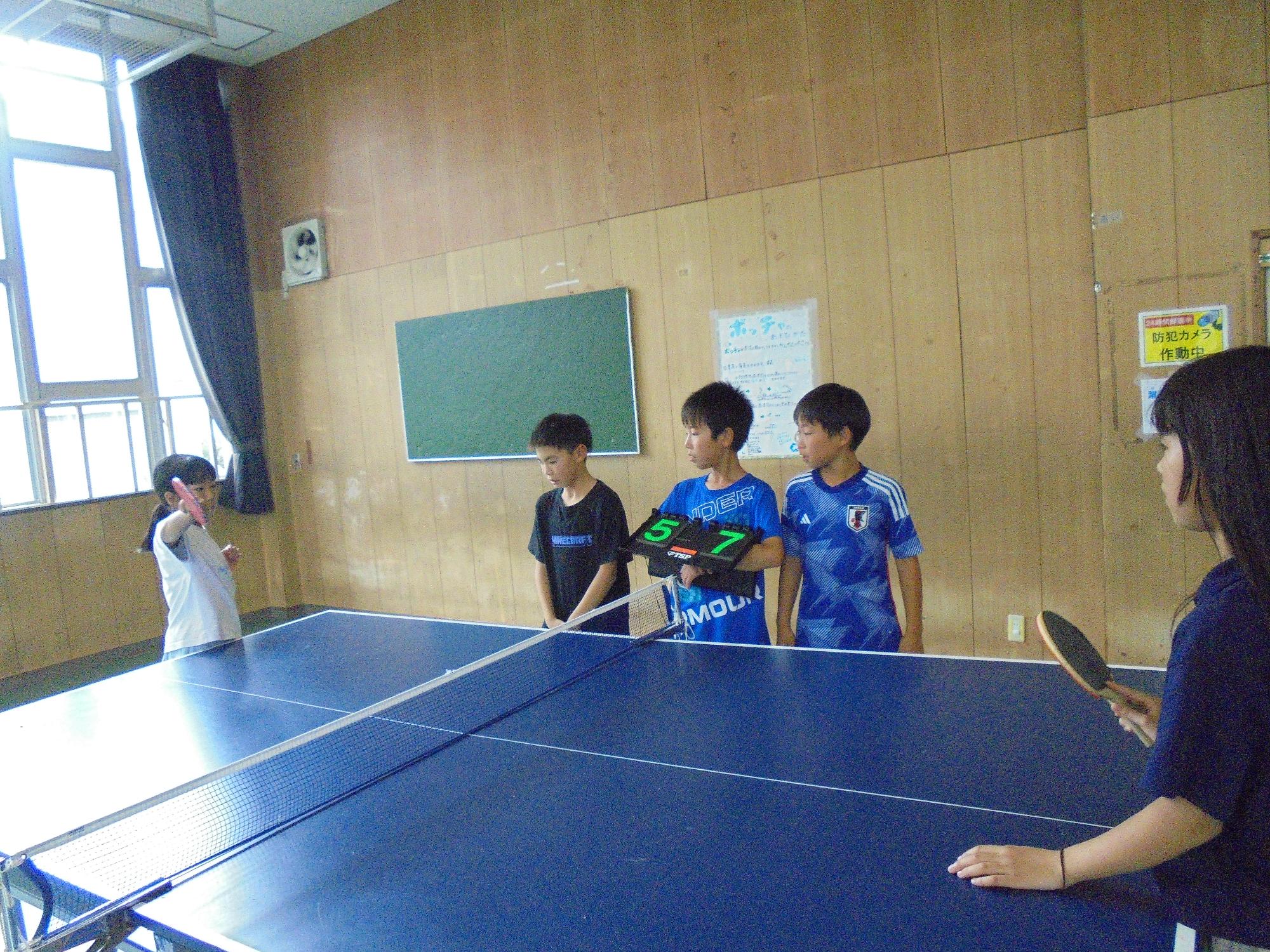 得点板を持って審判をする男子児童と試合をする女子児童の写真