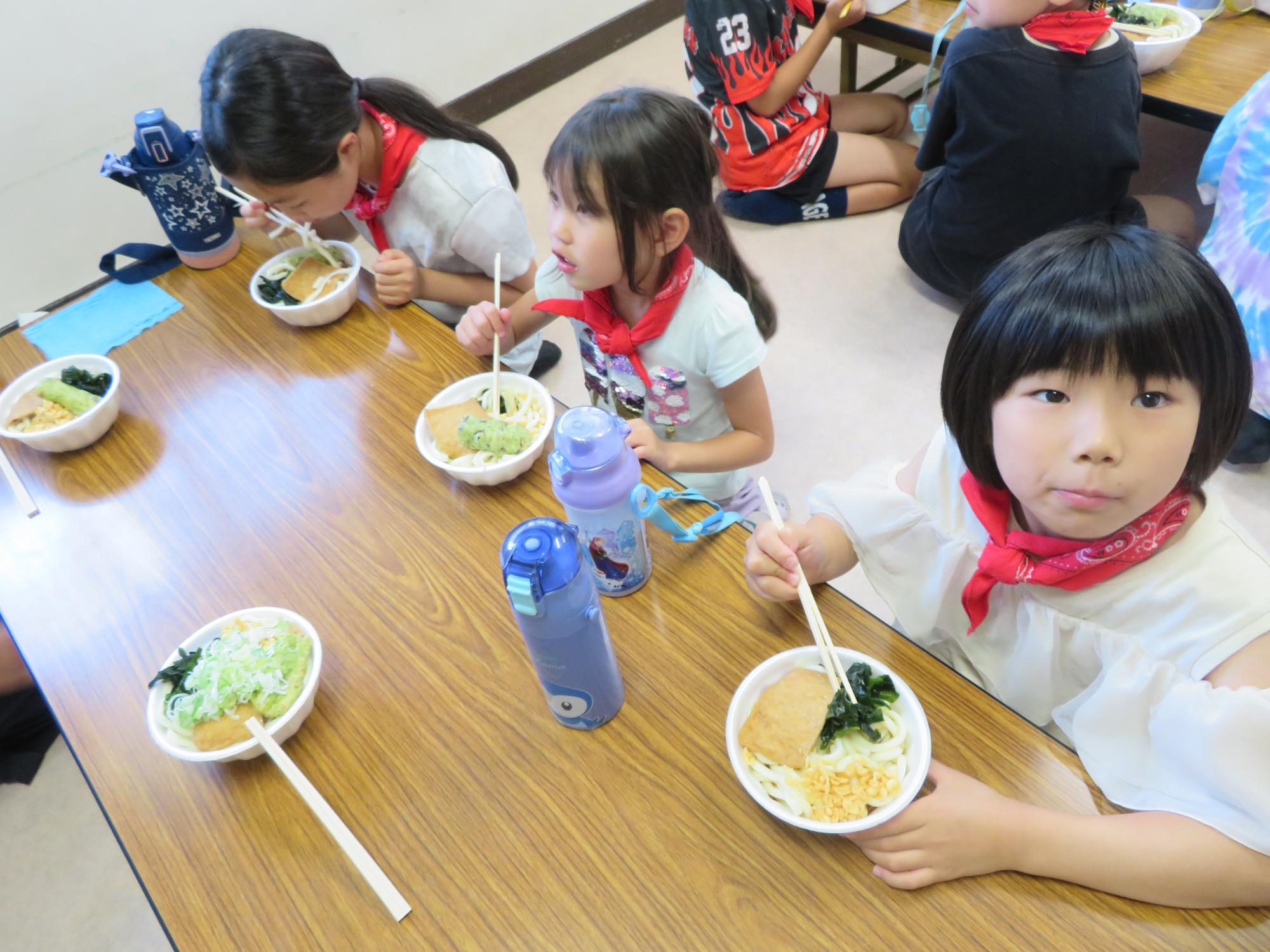図書室で並んでうどんをすする児童の写真