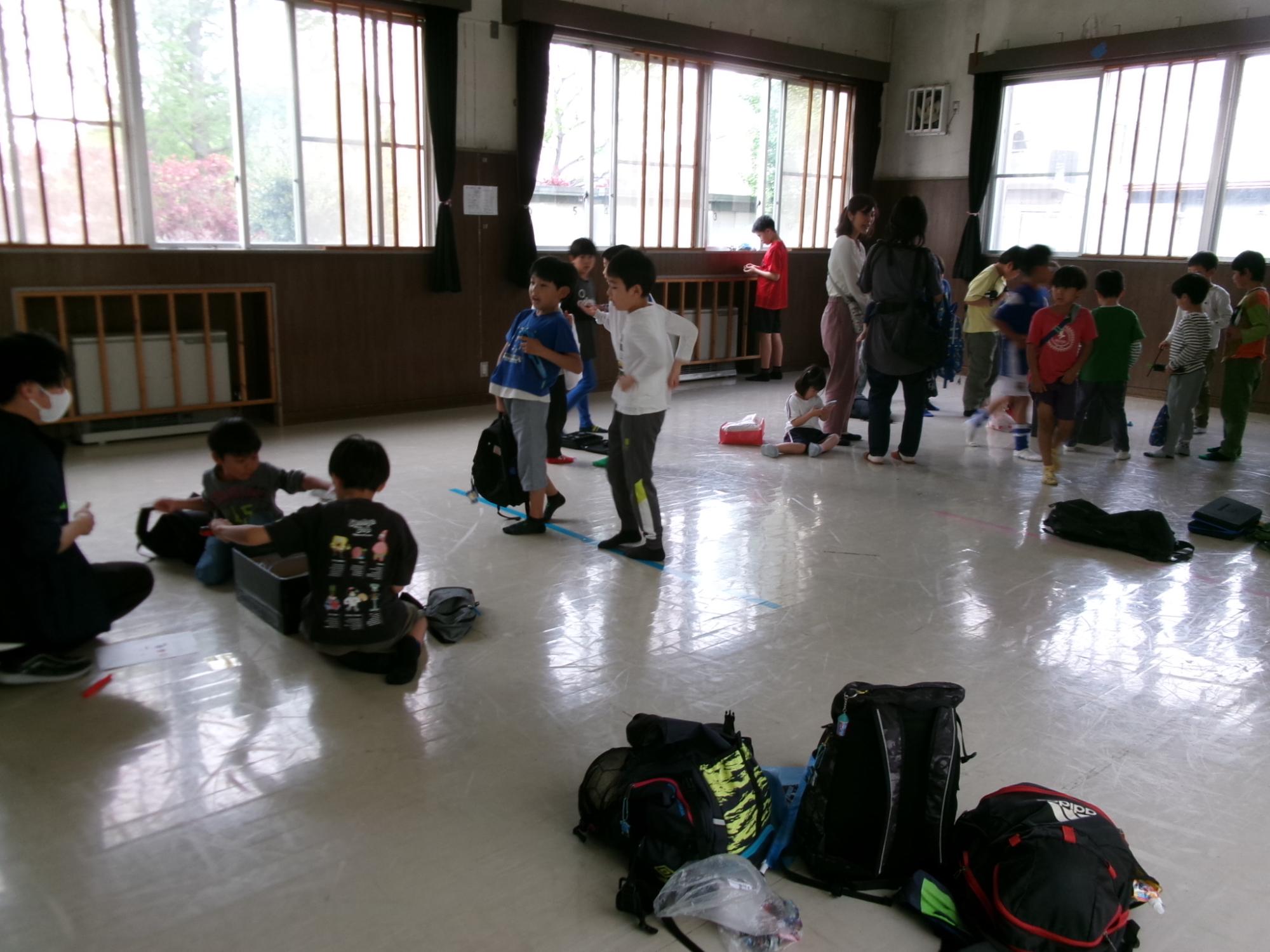 広い部屋に集まって子どもたちがベイブレードの大会に参加している様子の写真