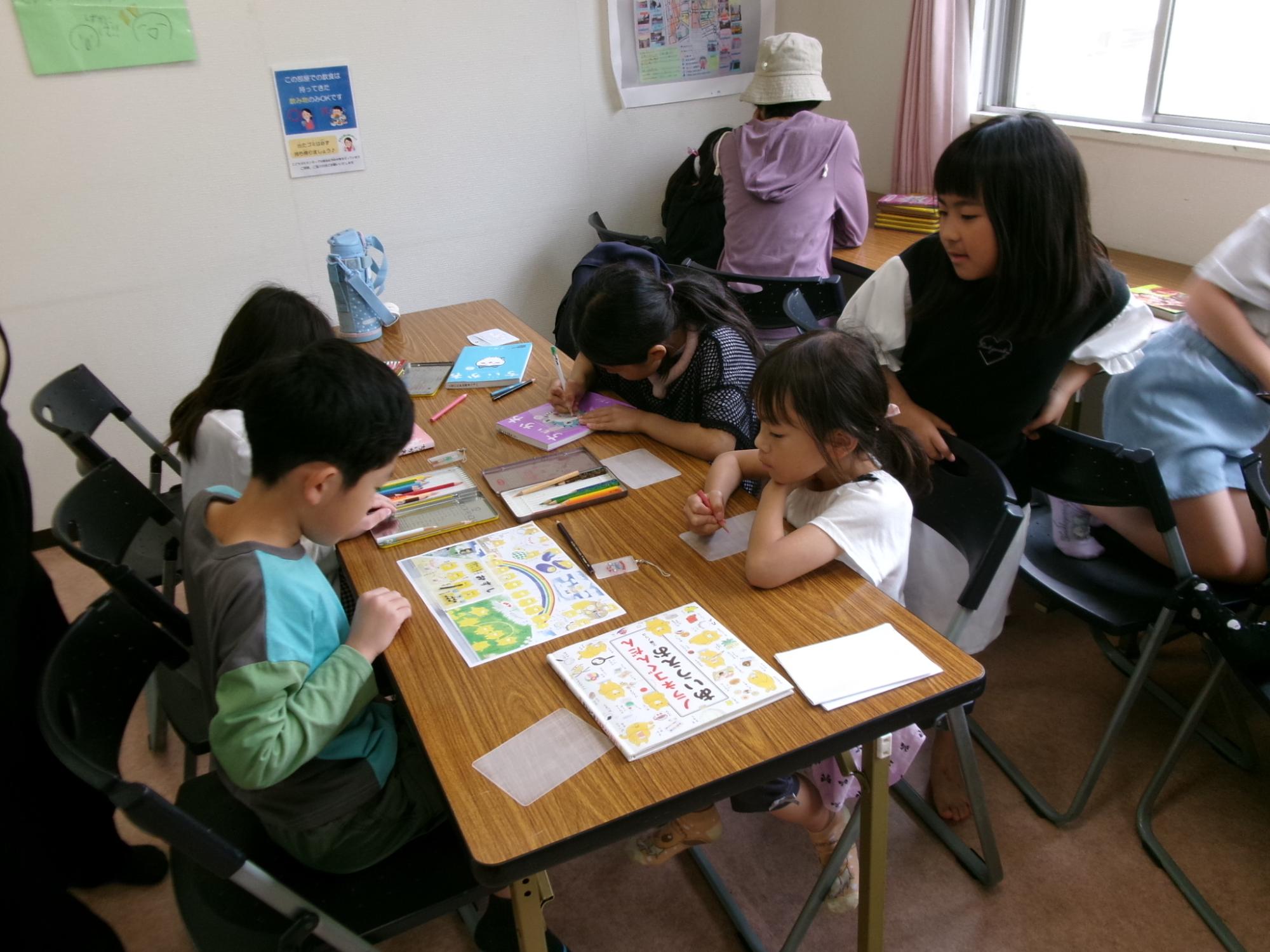 小学生が椅子に座りプラバンのイラストを描いている様子の写真