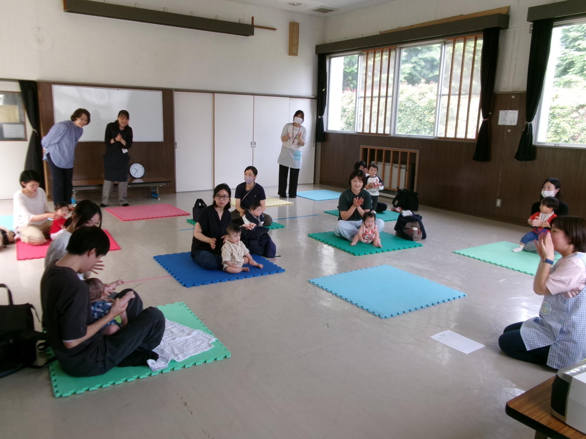 乳幼児親子がプレイマットの上で、自己紹介をしながらふれあい遊びをしている様子の写真