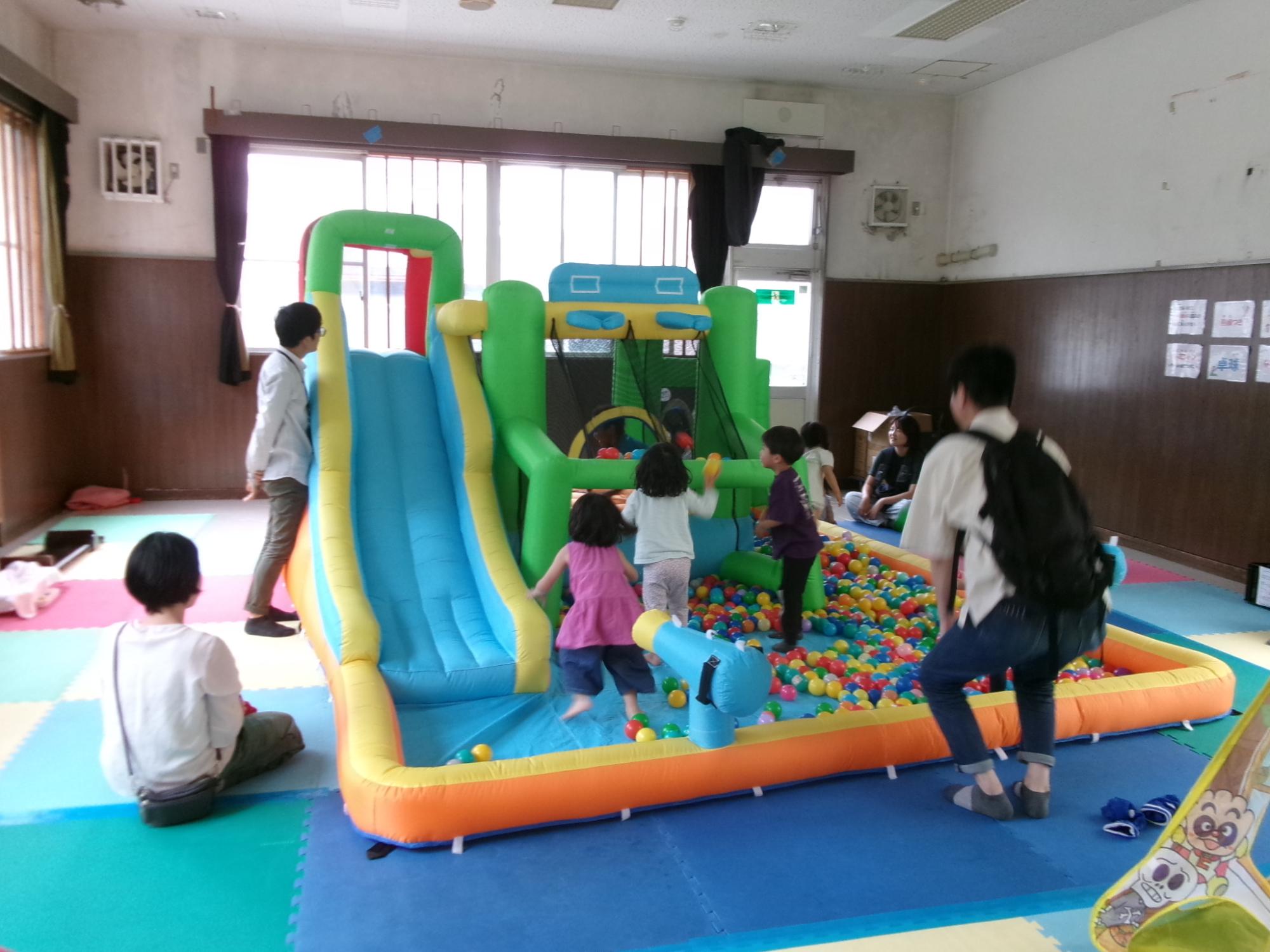 大きなボールプールやすべり台で遊んでいる幼児親子の様子の写真