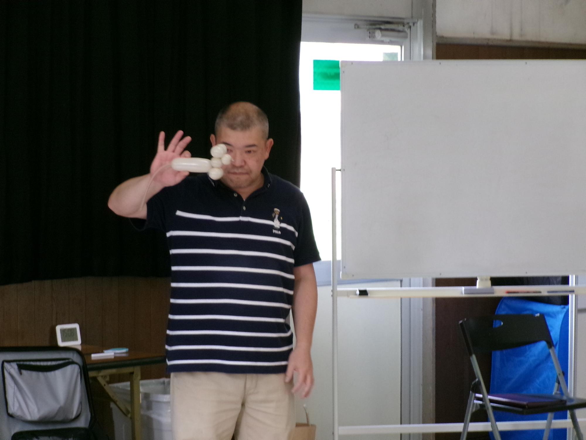 講師がバルーンアートの技を披露している様子の写真