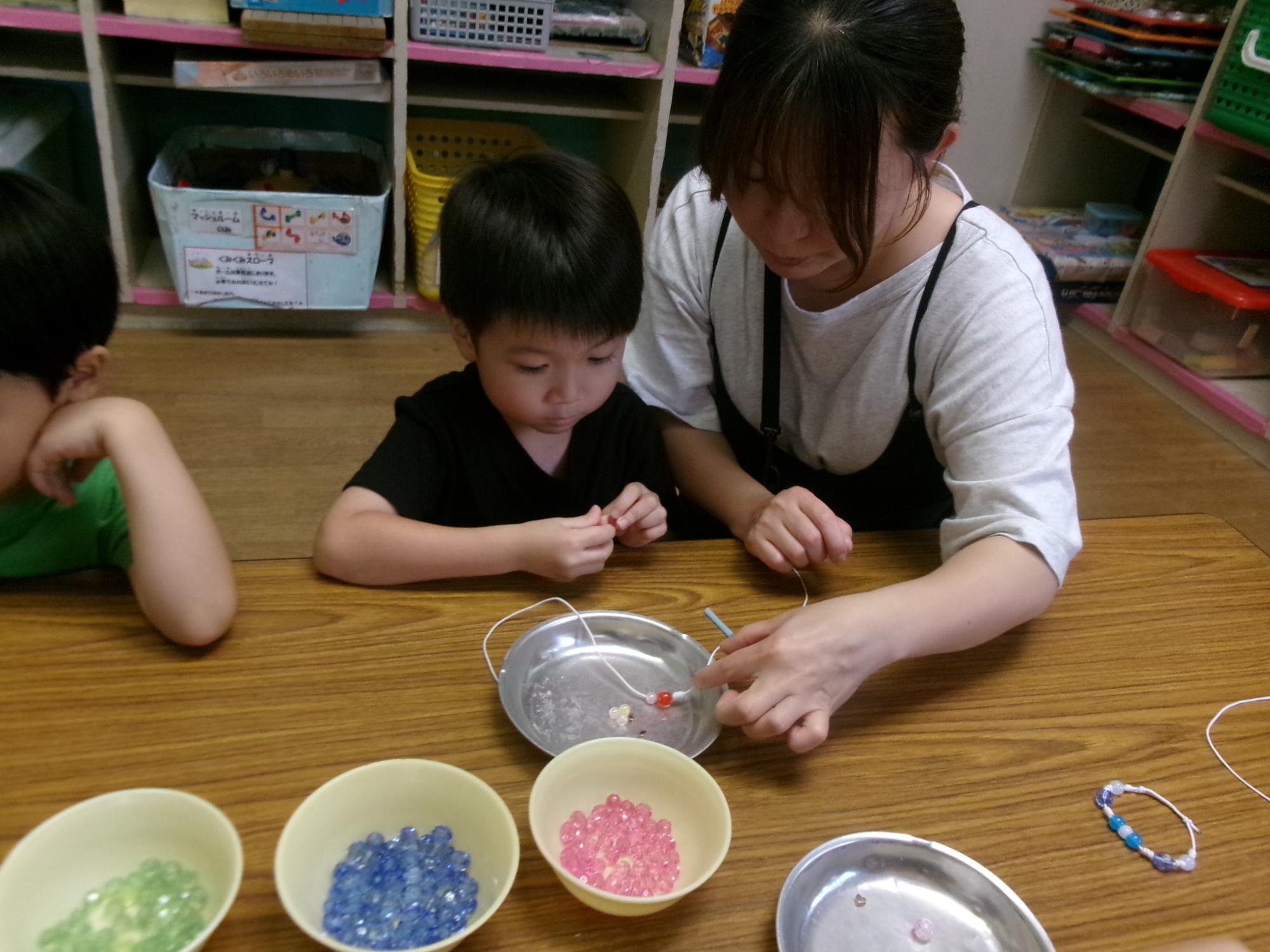 参加した幼児が紐にビーズを通している様子の写真