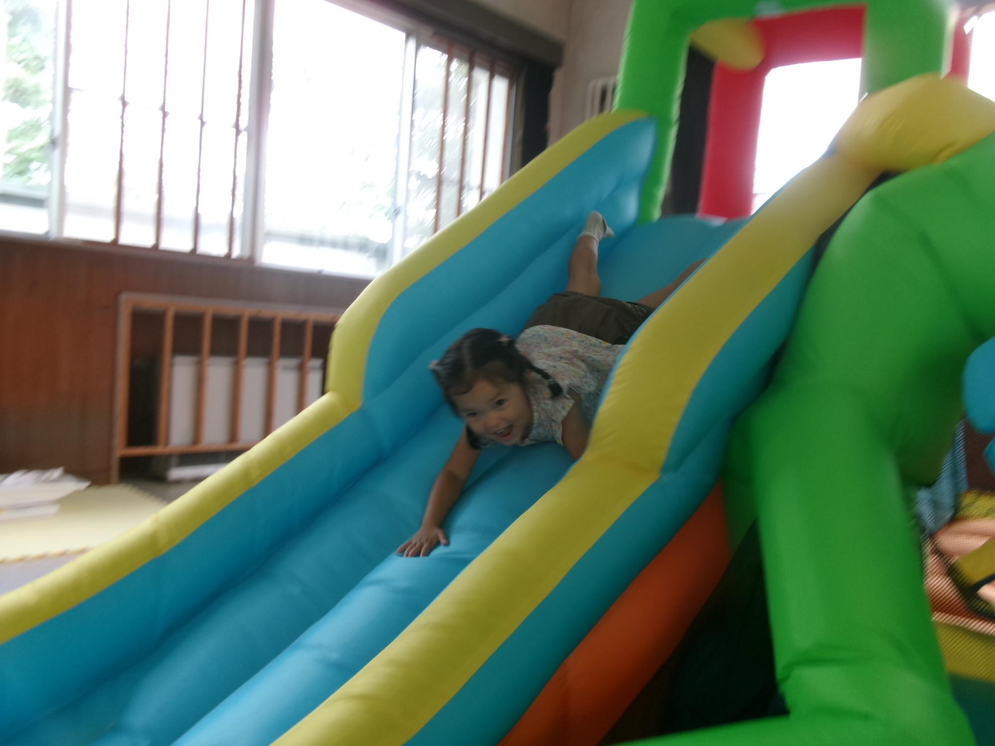 大きな滑り台から滑っている幼児の様子の写真