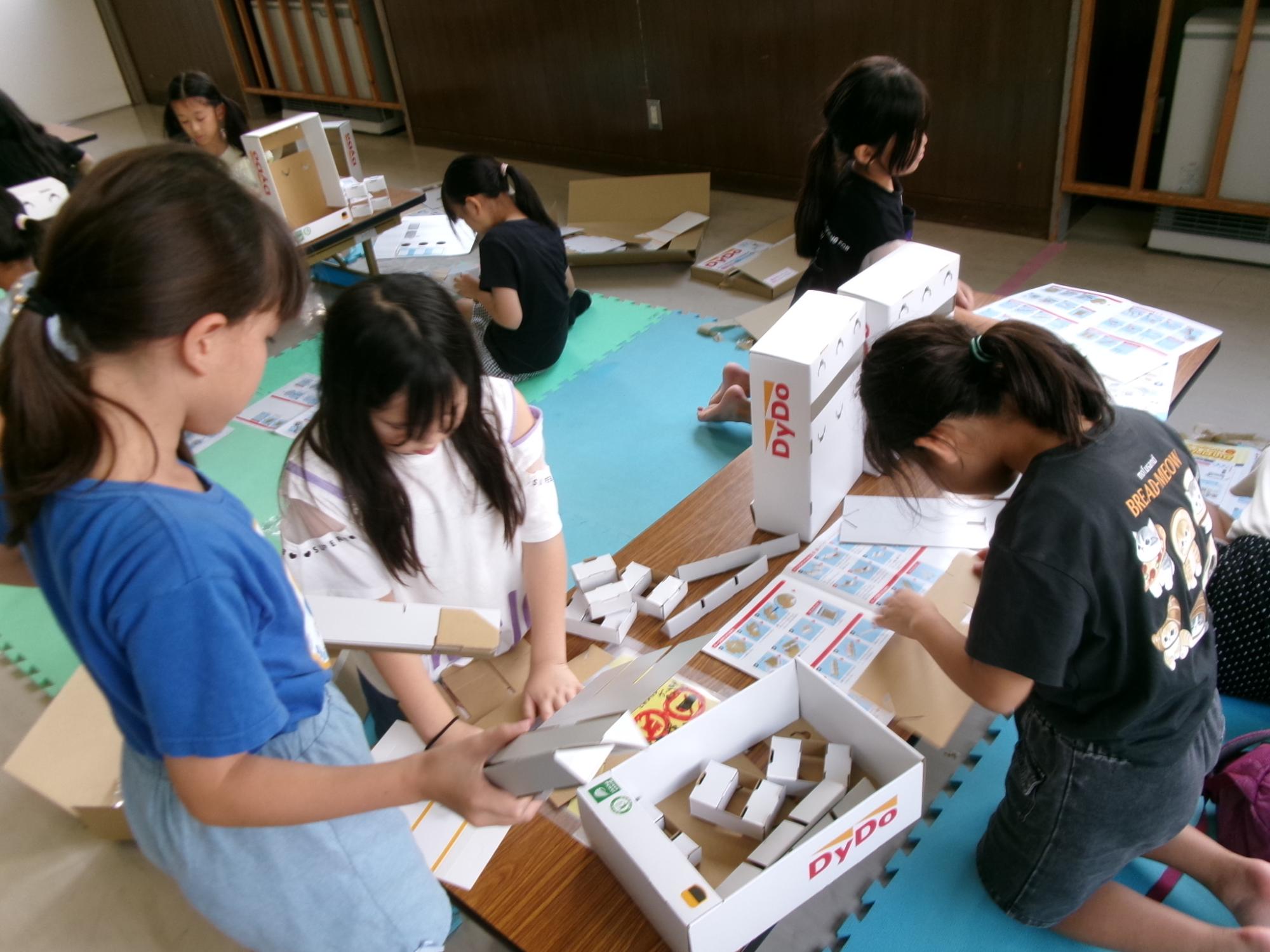 参加児童が自動販売機の貯金箱の工作をしている様子の写真