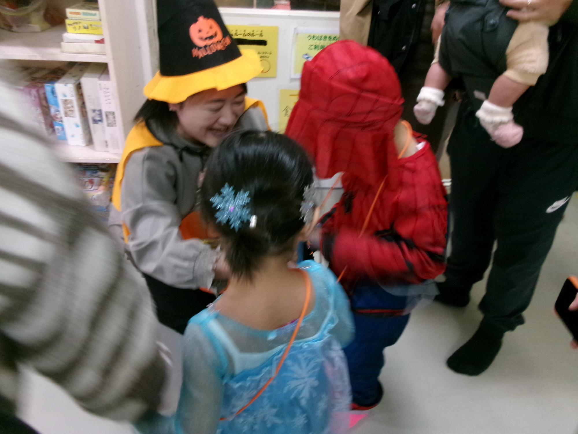 仮装をした子どもがお菓子をもらっている様子の写真