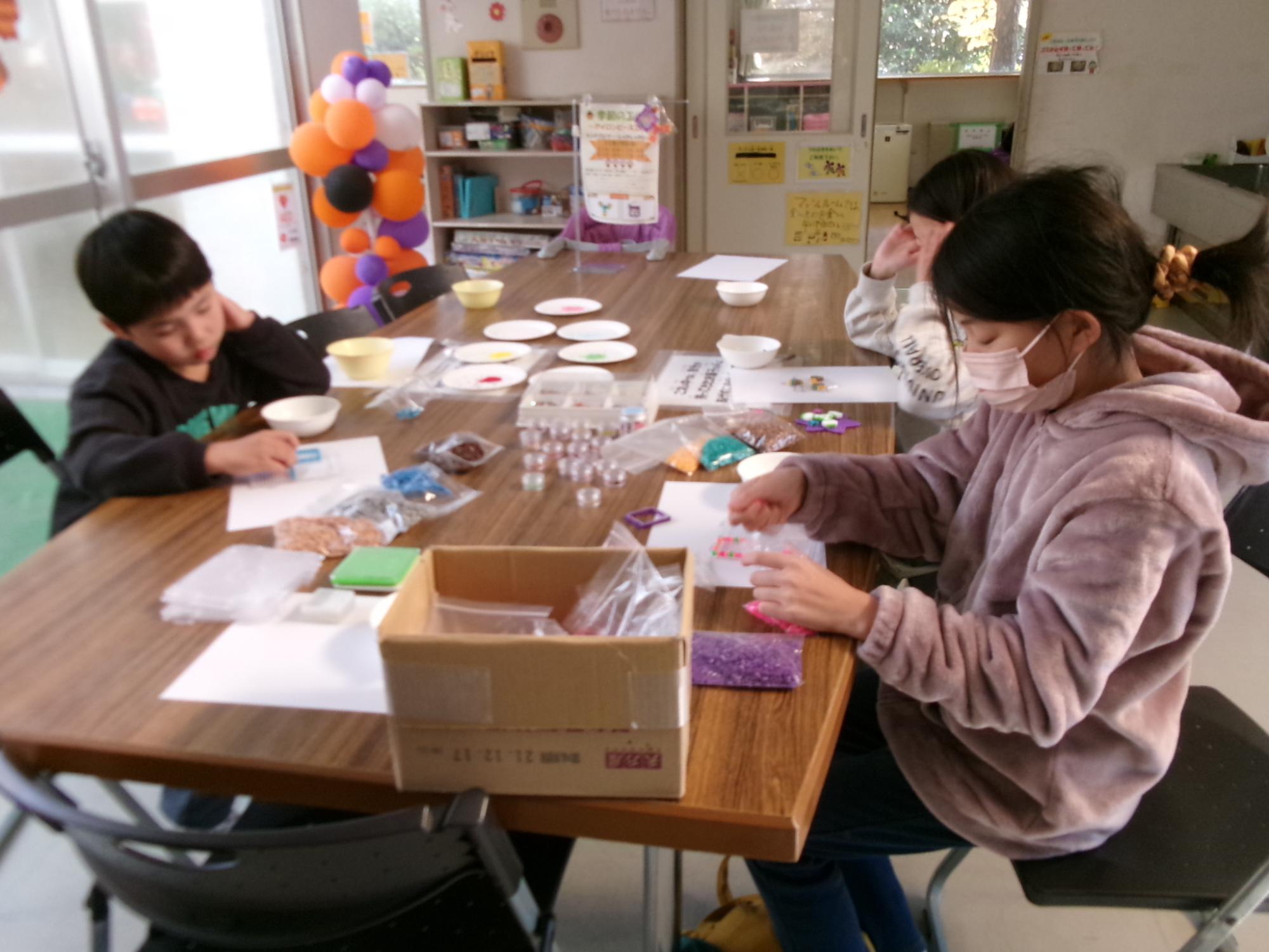 小学生がアイロンビーズ工作をしている様子の写真