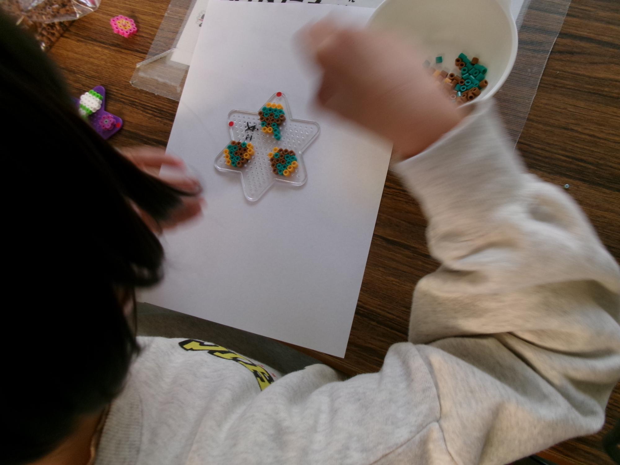 小学生がアイロンビーズでハンドスピナーを作っている様子の写真