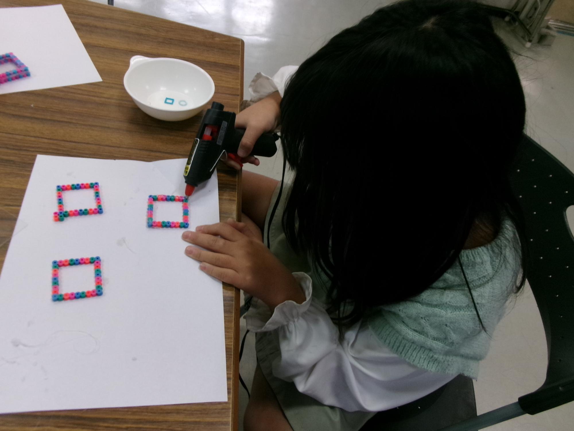 小学生がアイロンビーズでシャカシャカキーホルダーを作っている様子の写真