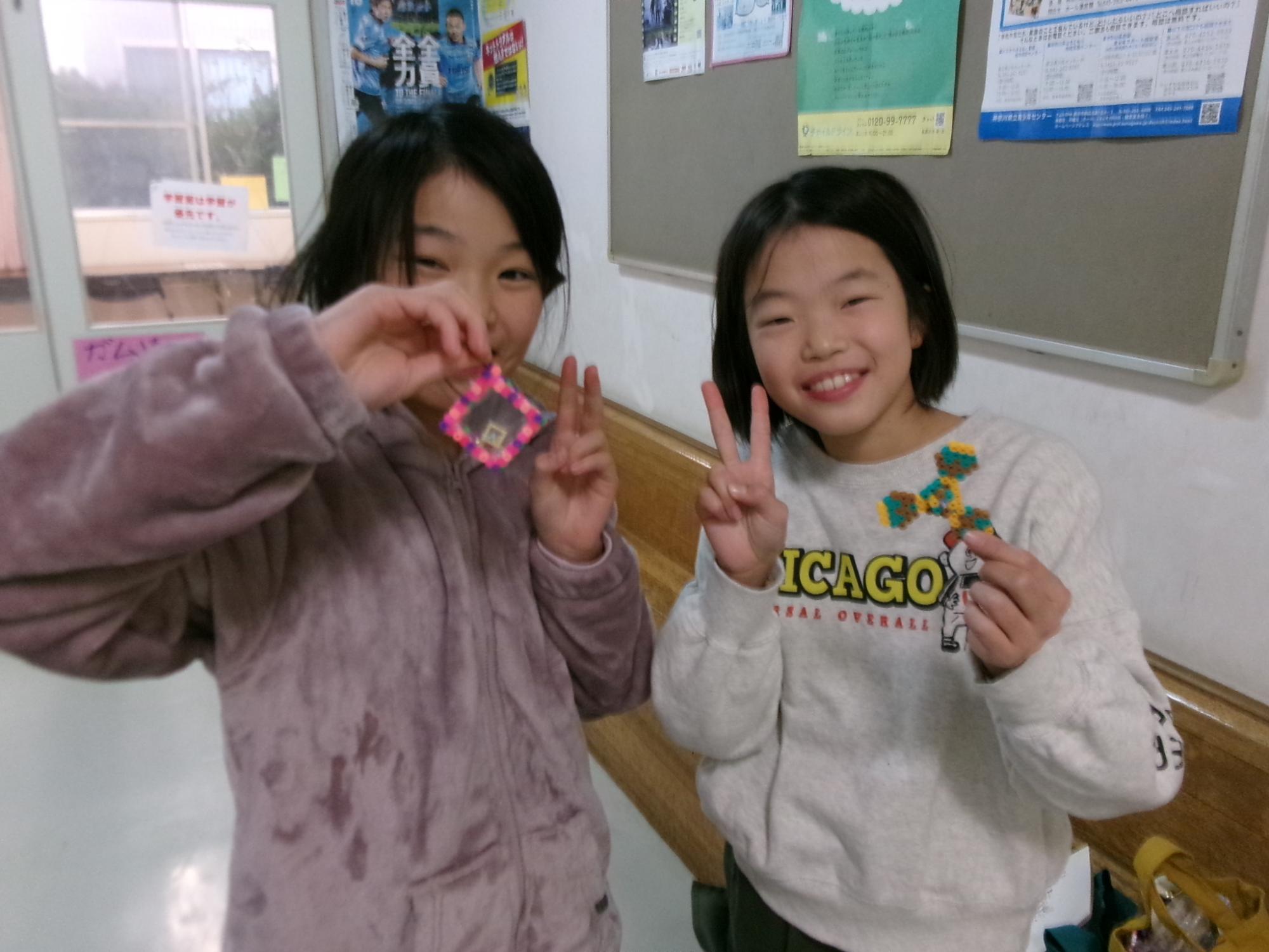小学生がアイロンビーズで作った作品を持っている写真
