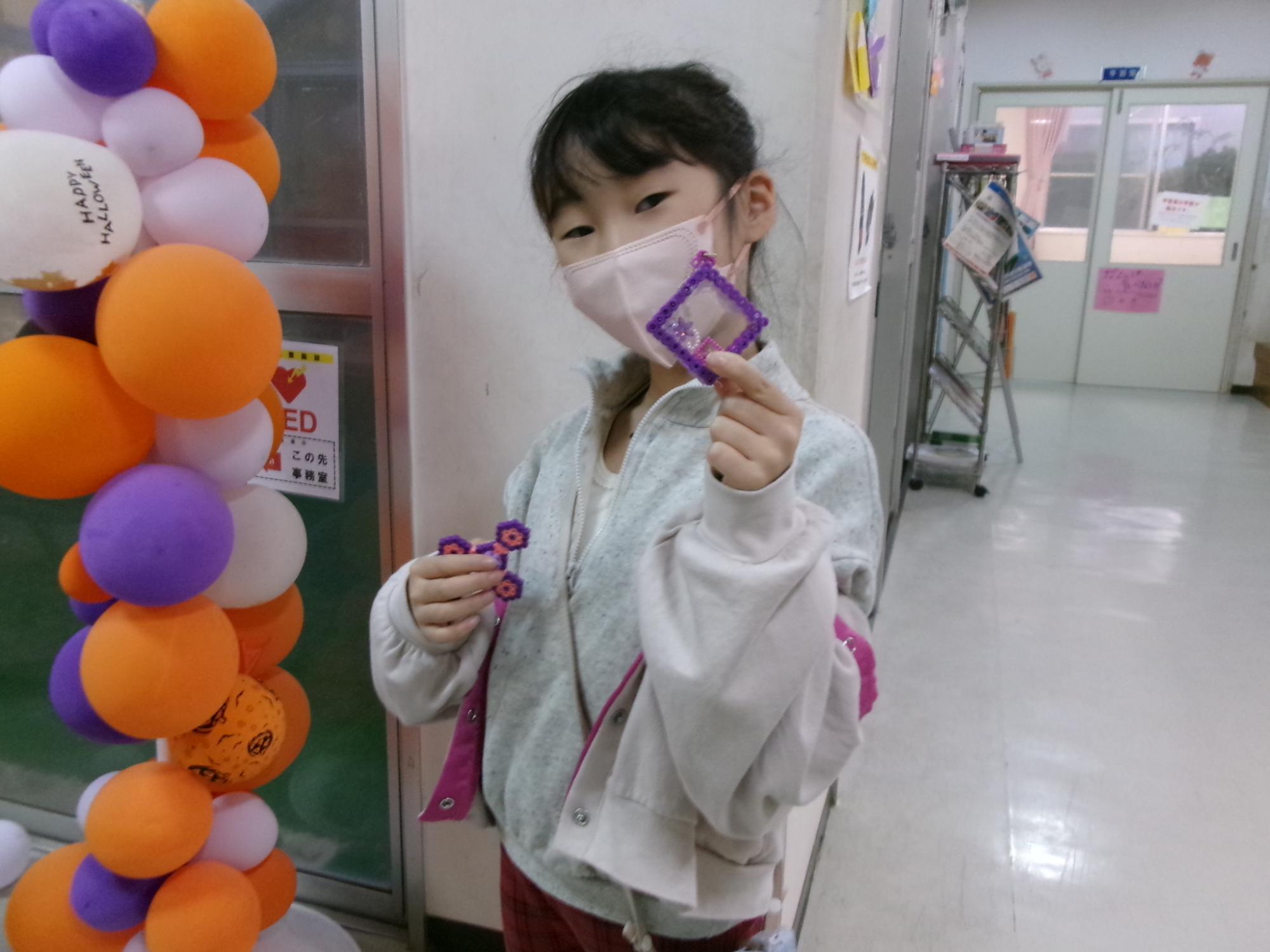 小学生がアイロンビーズ捏っくた作品を持っている写真