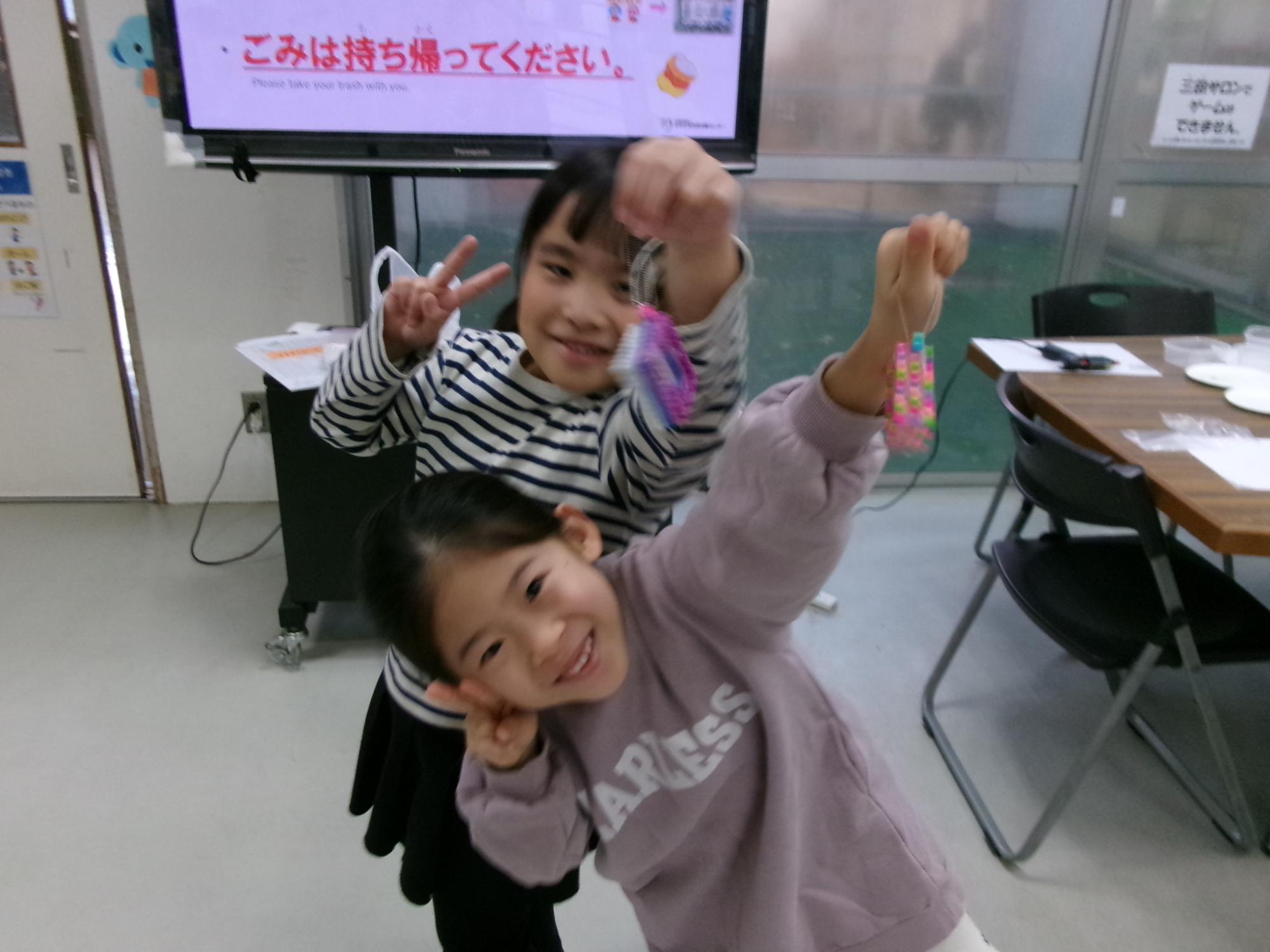 小学生がアイロンビーズで作った作品を持っている写真