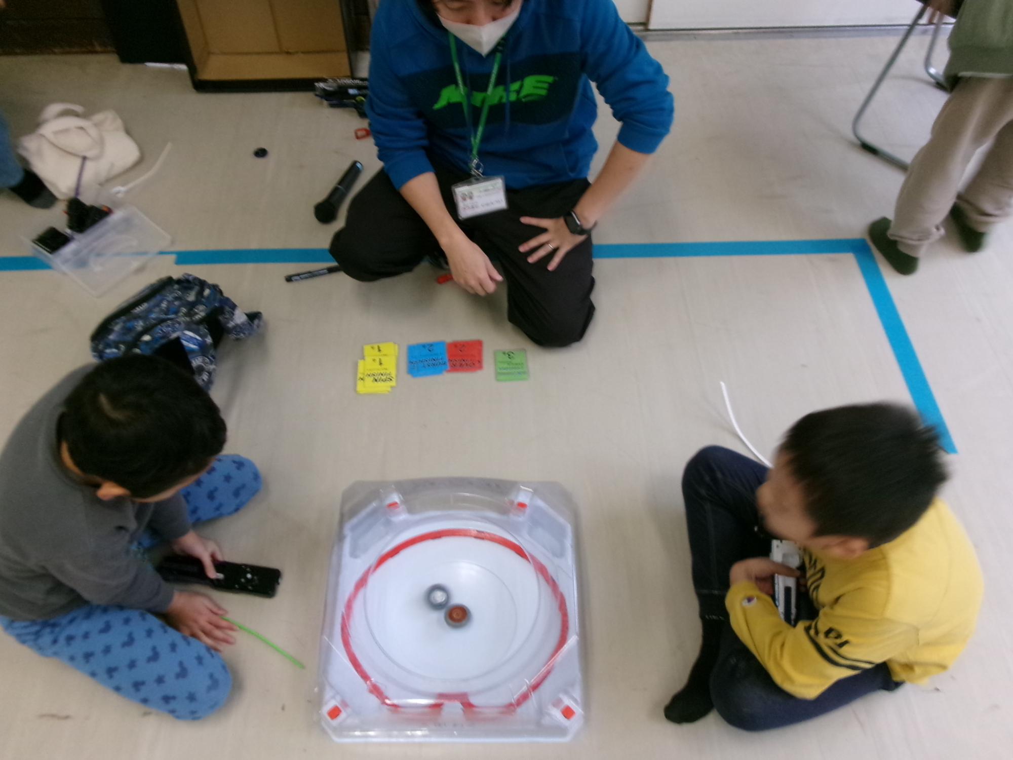 小学生がベイブレード大会で対戦している様子の写真