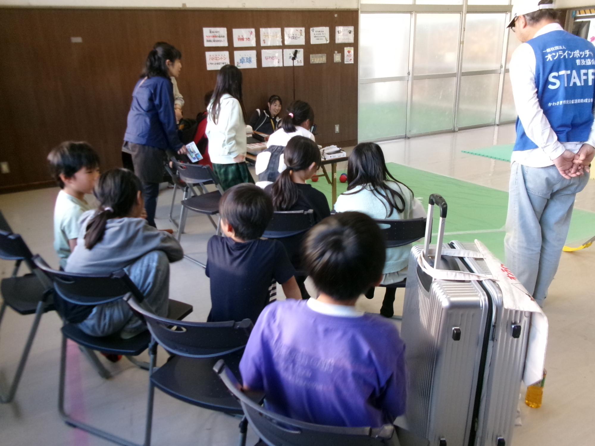 小学生がオンラインボッチャで対戦していて後ろで観戦している様子の写真