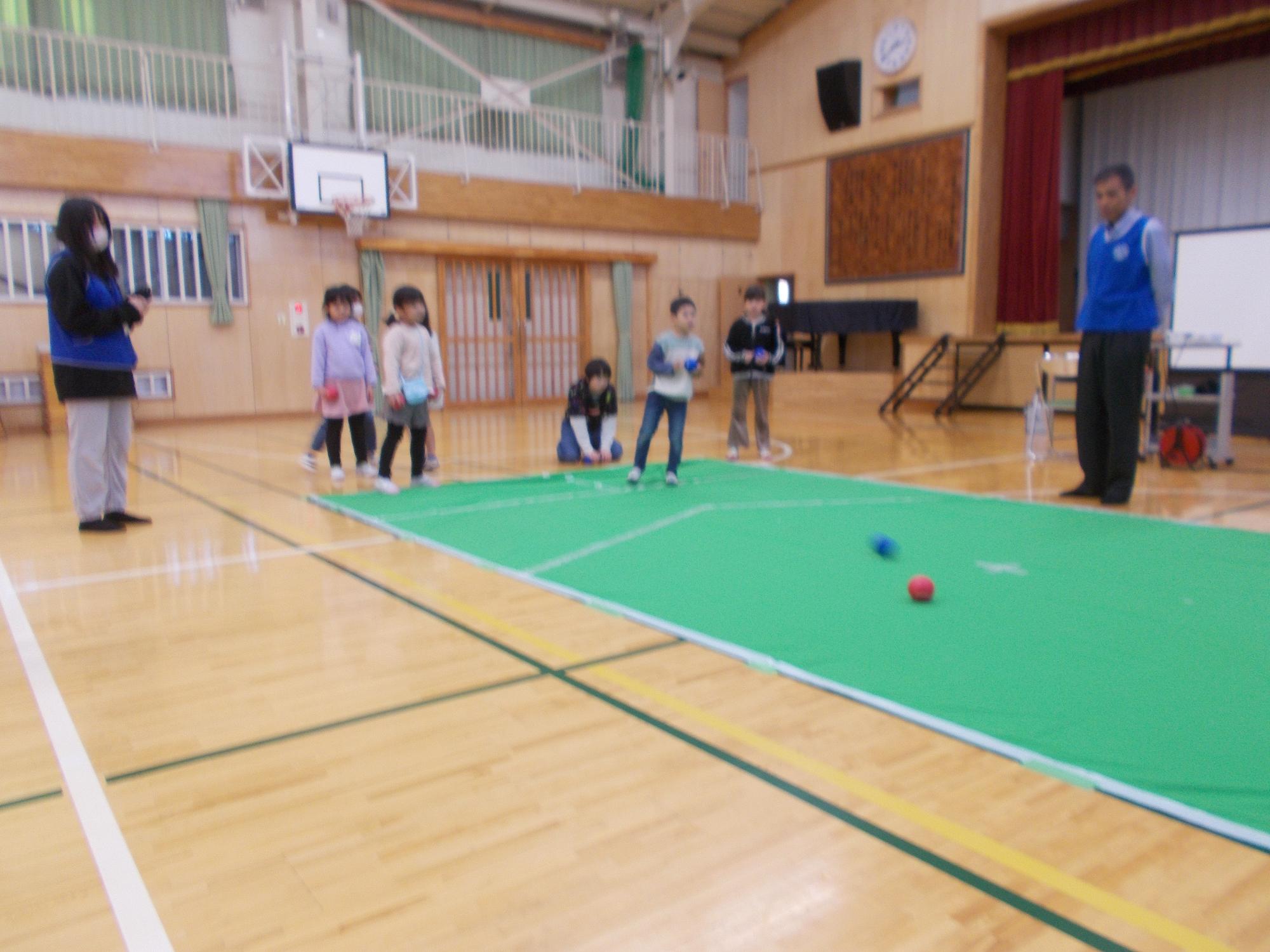 小学生が体育館でボッチャをの体験をしている様子の写真