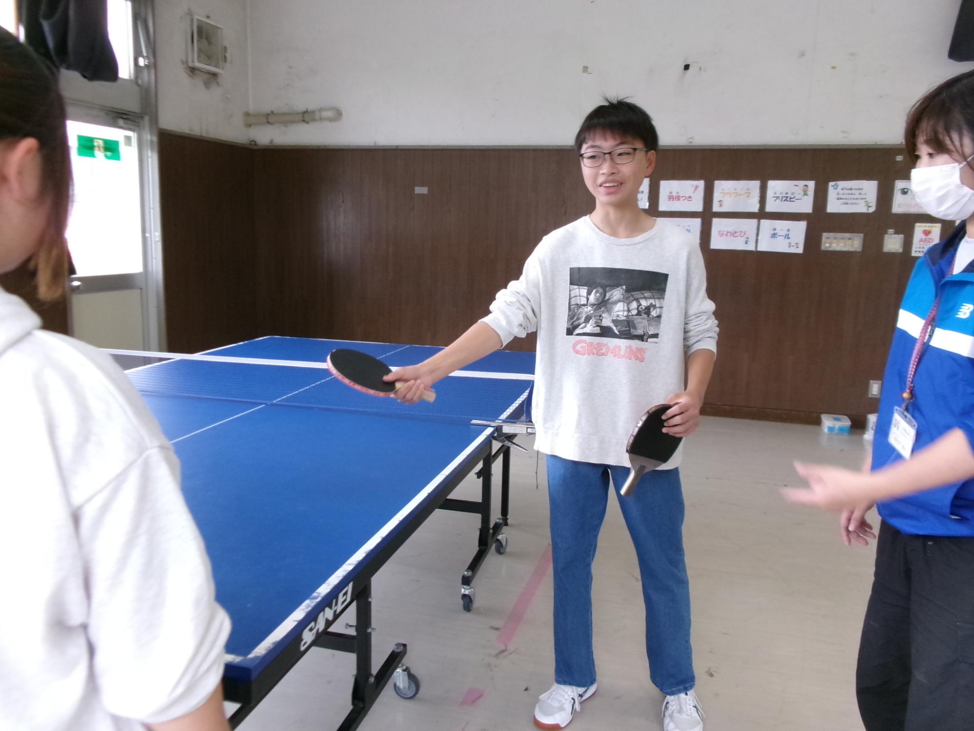 中学生が小学生に卓球を教えている様子の写真