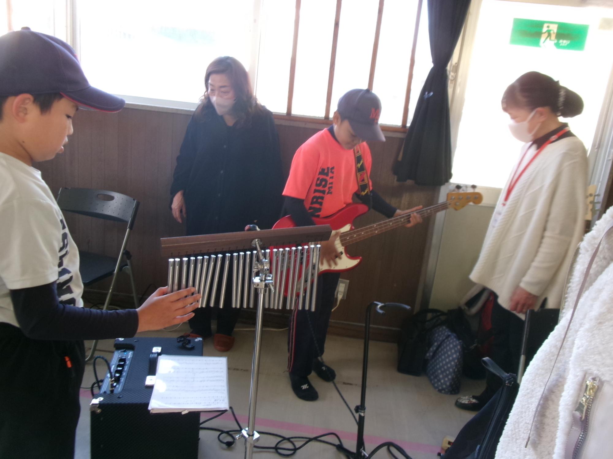 クレイジーミタバンドの皆さんの楽器の演奏体験をさせてもらっている子どもの写真