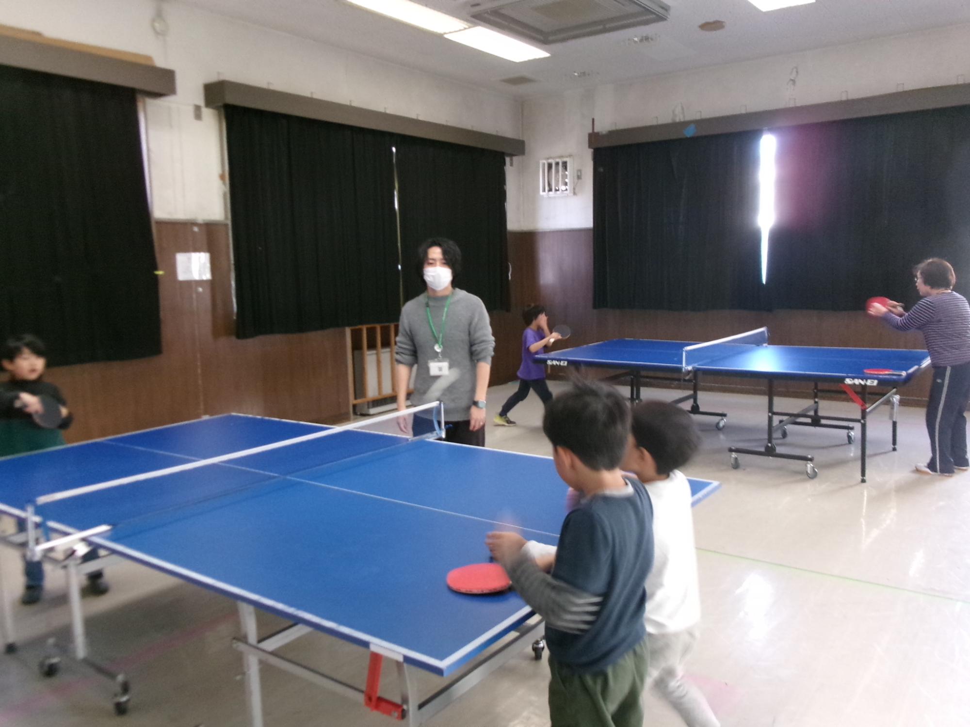 教わりながら卓球をしている子どもたちの写真