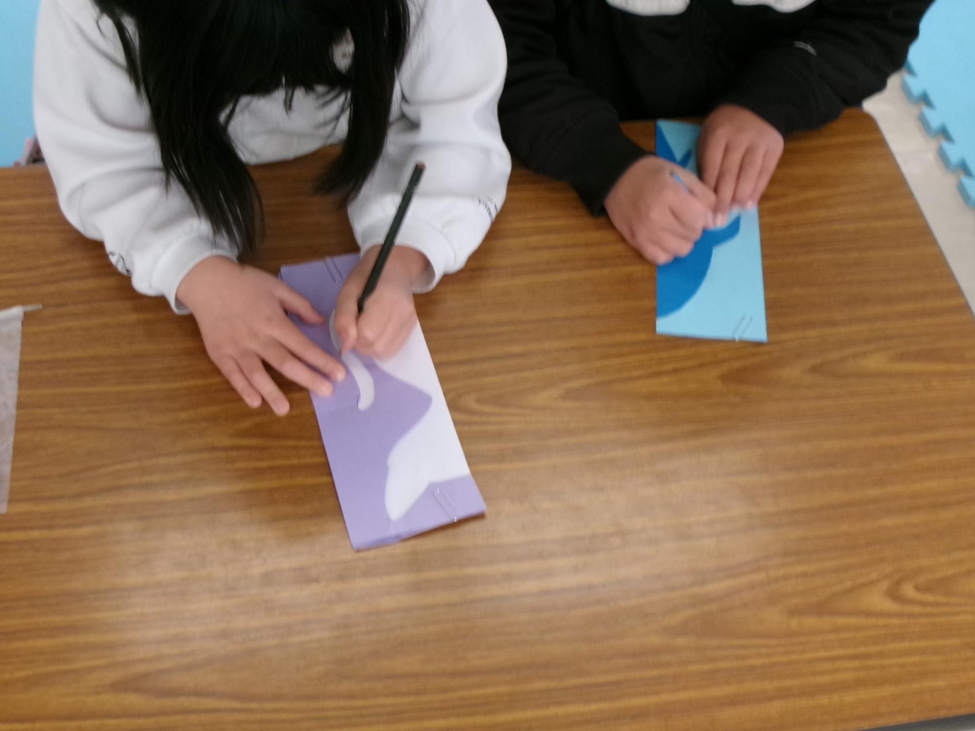 参加児童が大薗さんの作品の台紙を使って下書きをしている様子の写真
